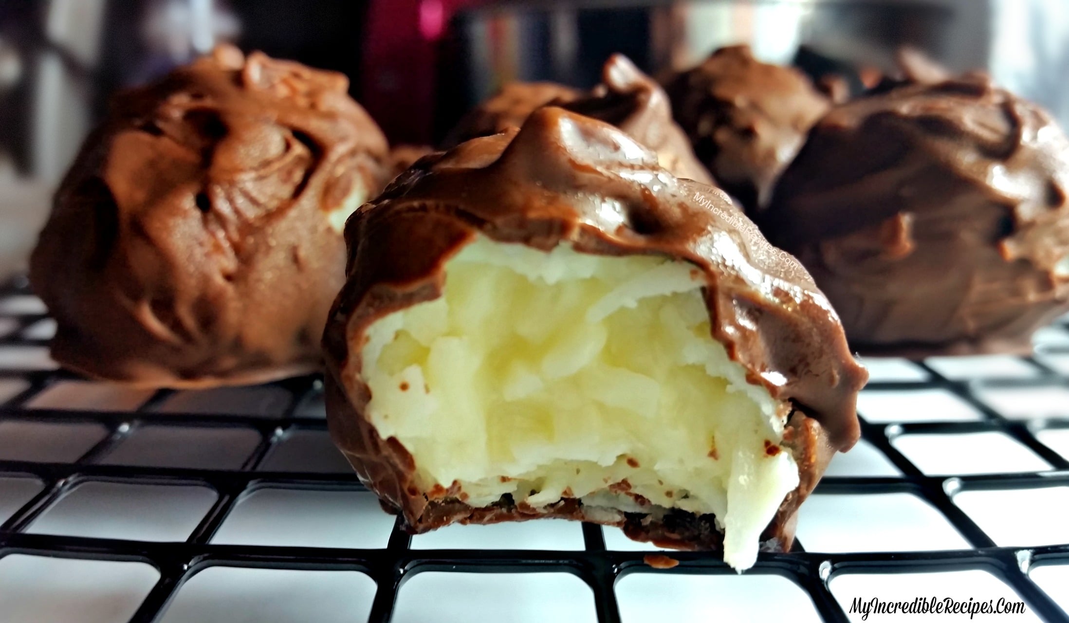 Mounds Coconut Copycat Chocolate Balls on a wire cooling rack with a bite missing from the front one