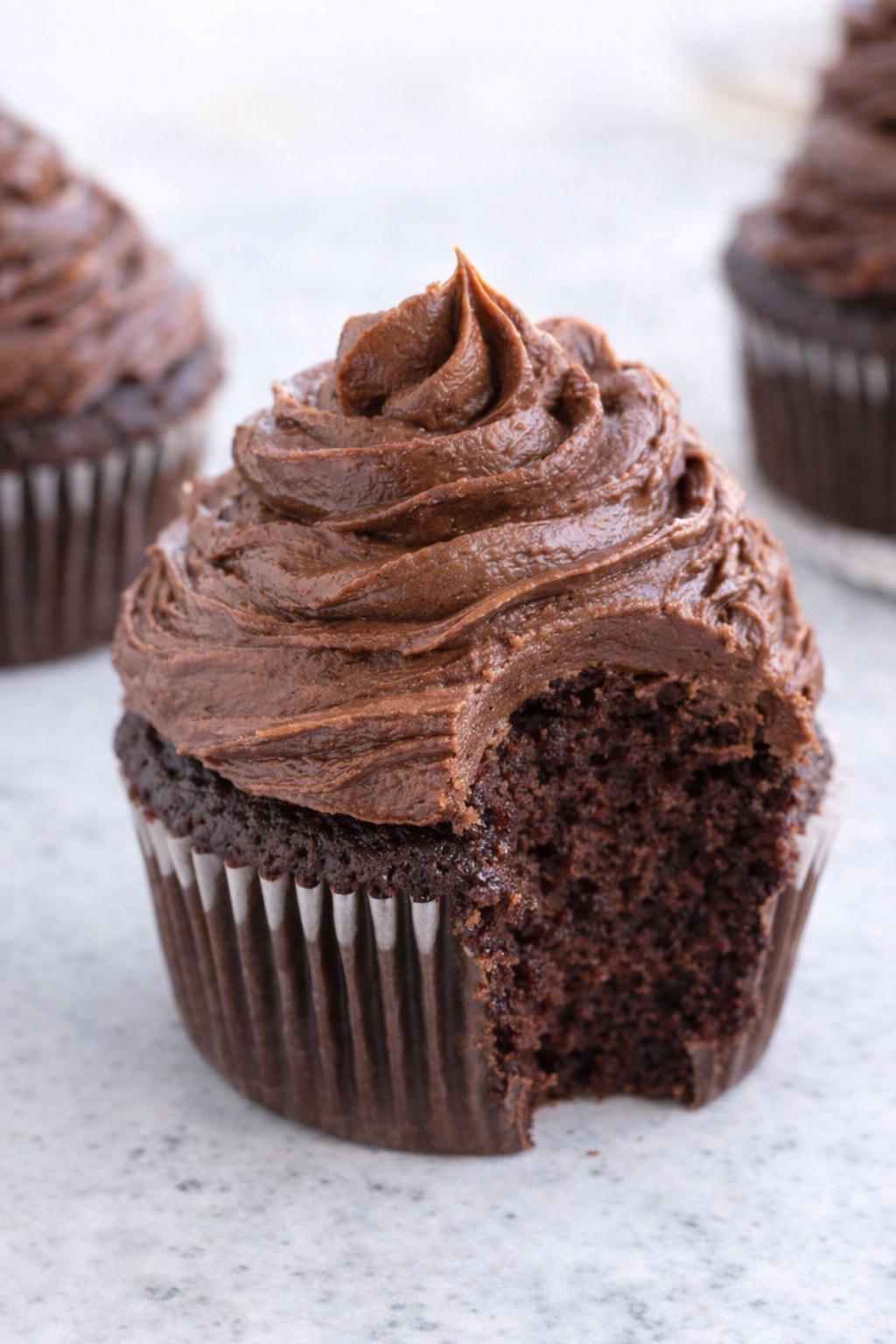 Chocolate Cupcake with a bite missing topped with the Chocolate Buttercream Frosting