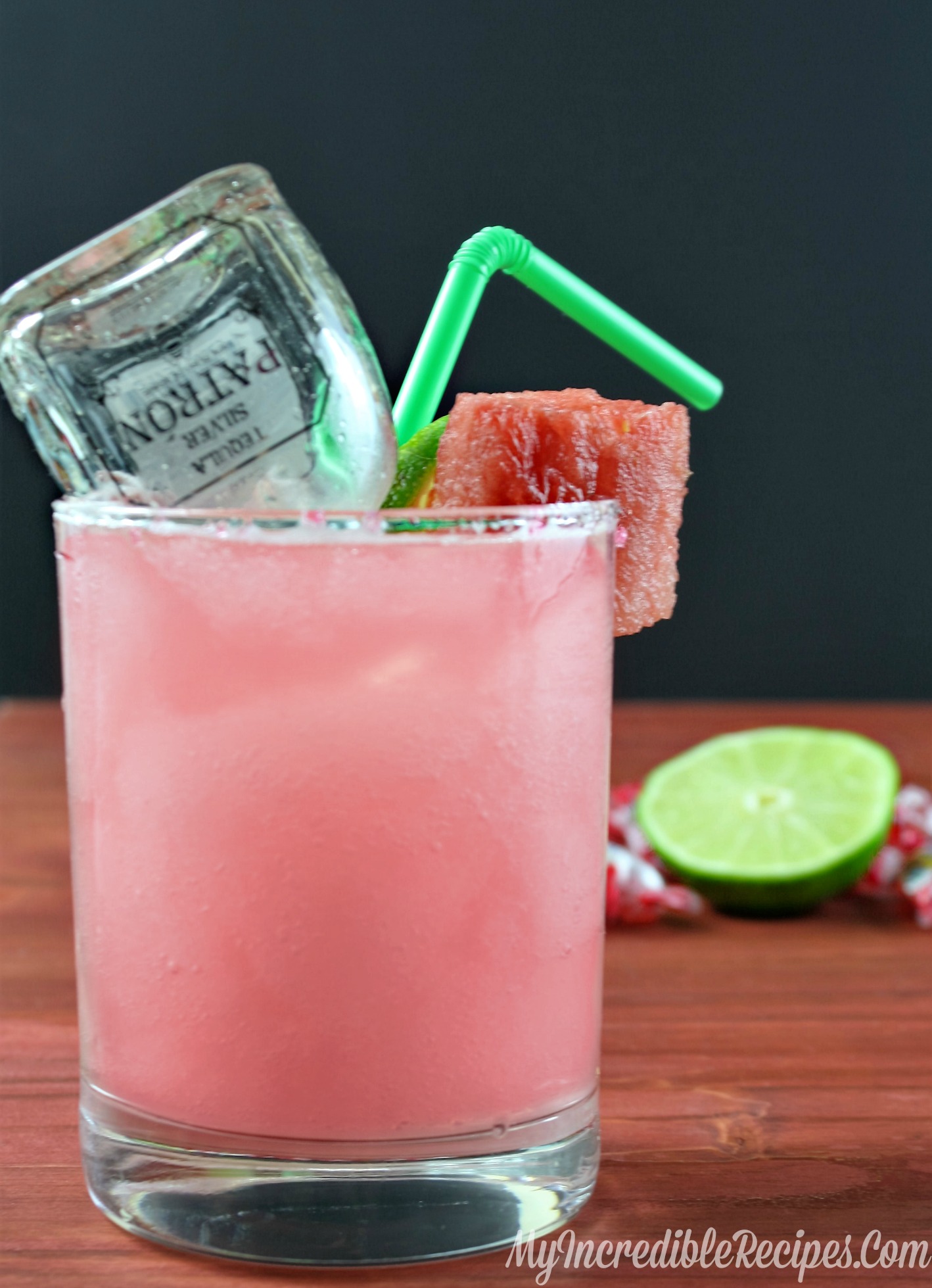 watermelon margarita on a wood table with a mini bottle of patron inside and a green straw