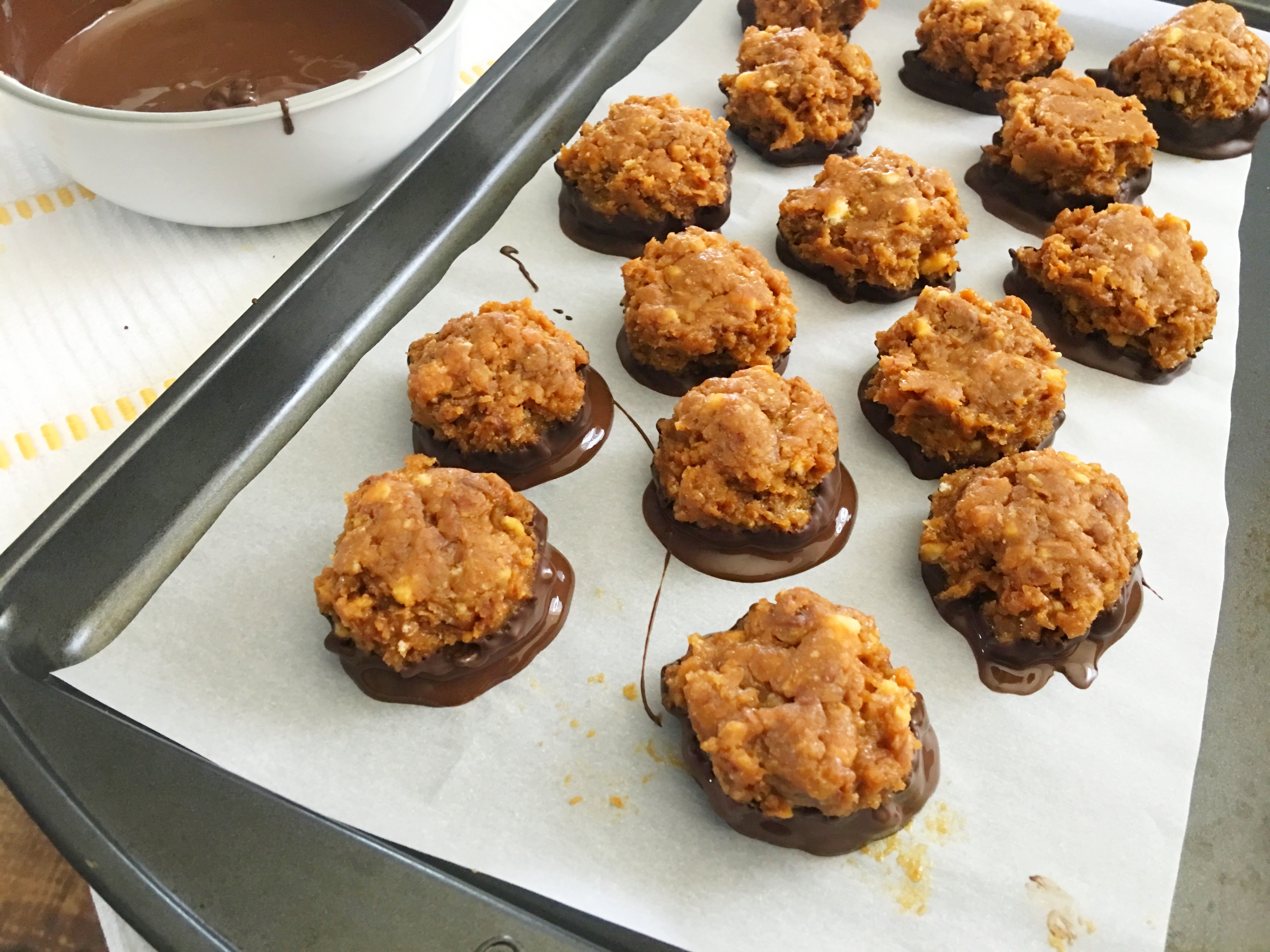 Samoa Bites on a parchment paper lined baking sheet dipped in chocolate
