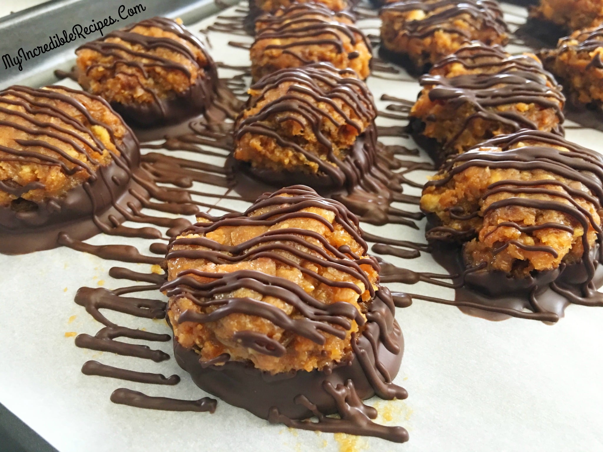 up close Samoa Bites on a parchment paper lined baking sheet drizzled with chocolate