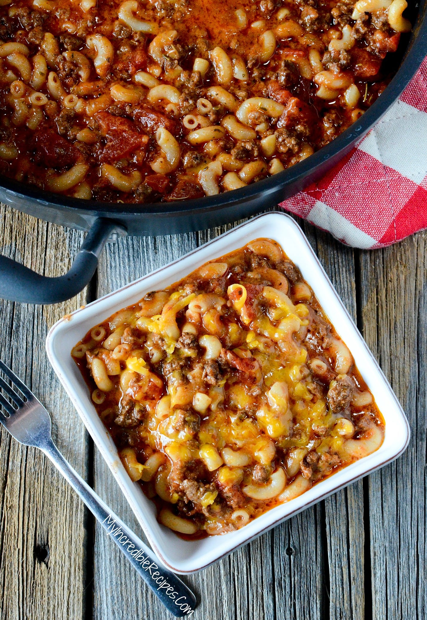 Old Fashioned Goulash in a pot with a white bowl filled with some topped with cheese