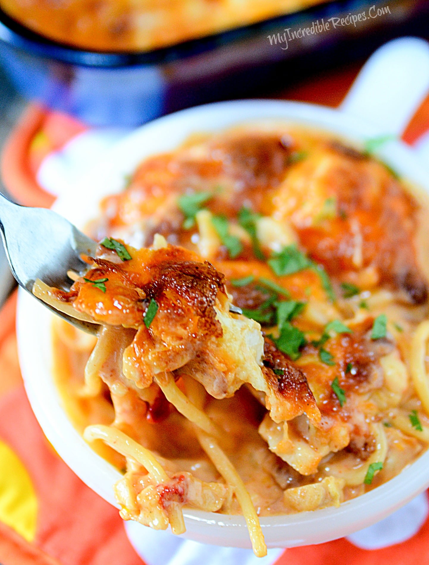 Cheesy Chicken Spaghetti in a white bowl with a fork lifting up a bite