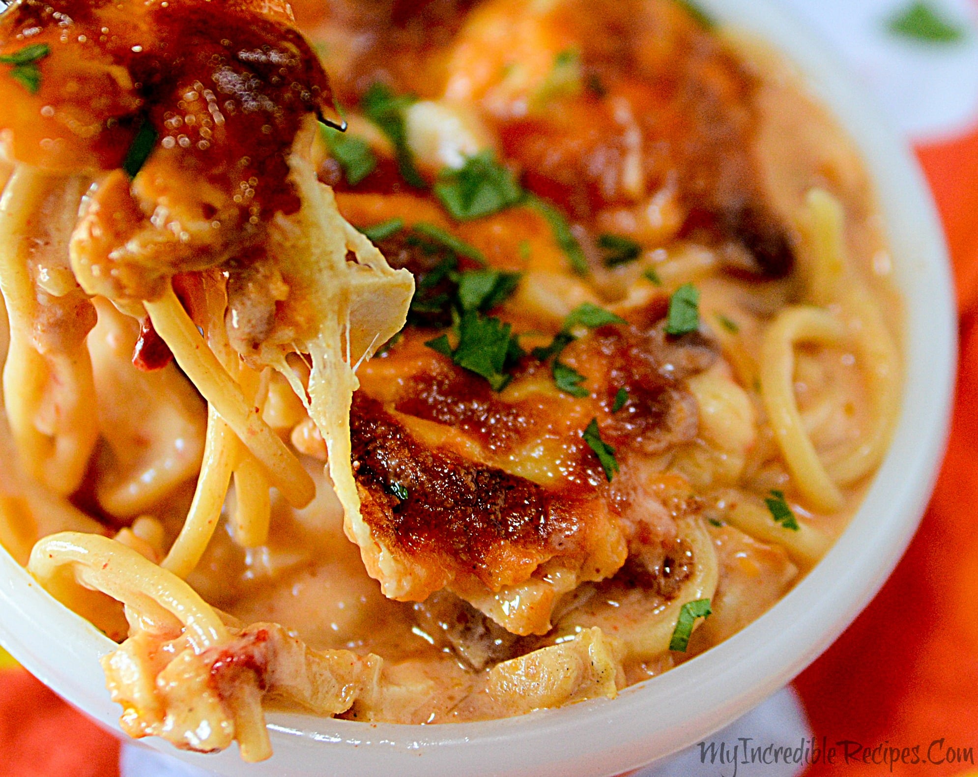 side view of the Cheesy Chicken Spaghetti in a white bowl with a fork lifting up a bite