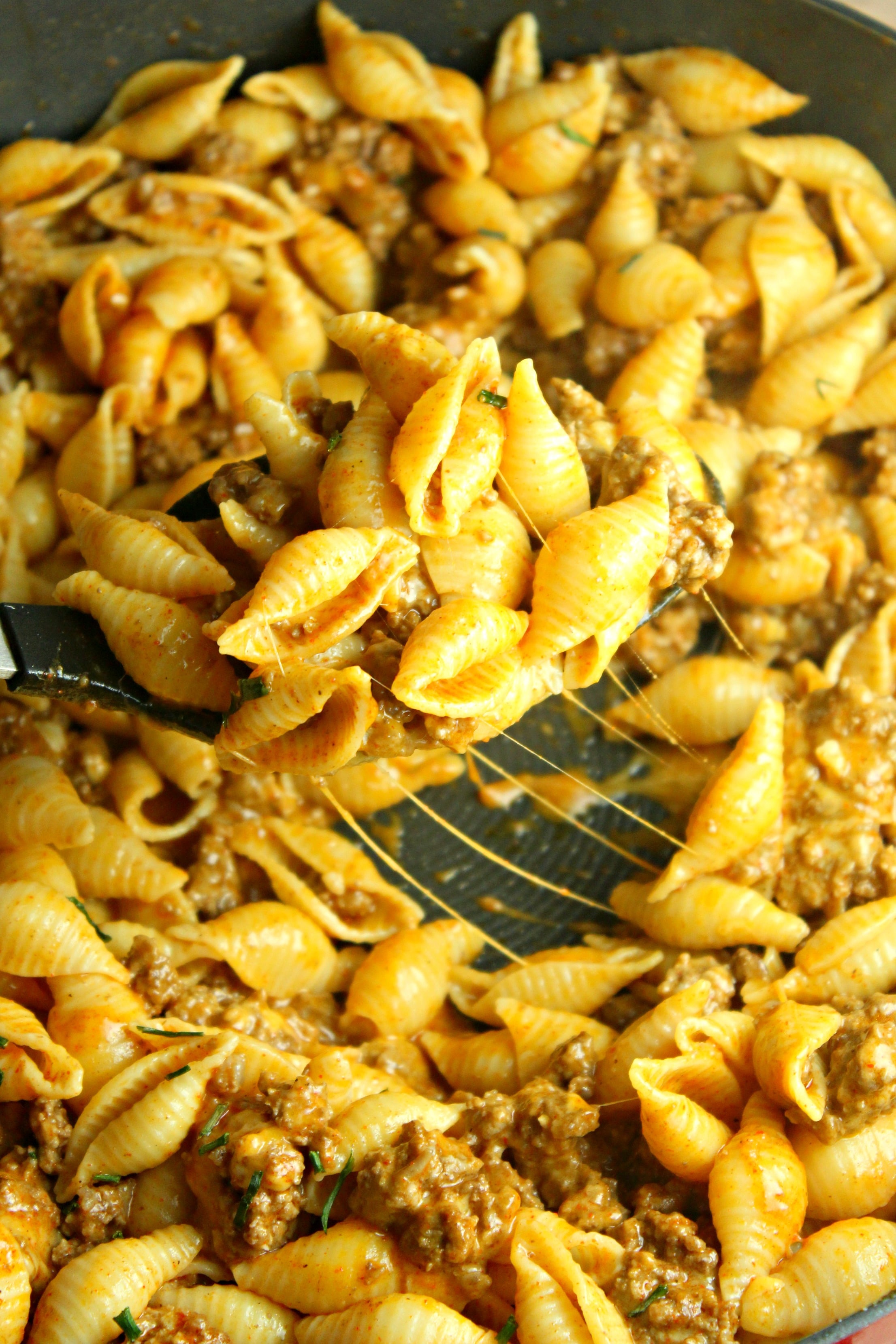 Cheesy Taco Pasta Shells in a red pan with a spoon lifting up a bite