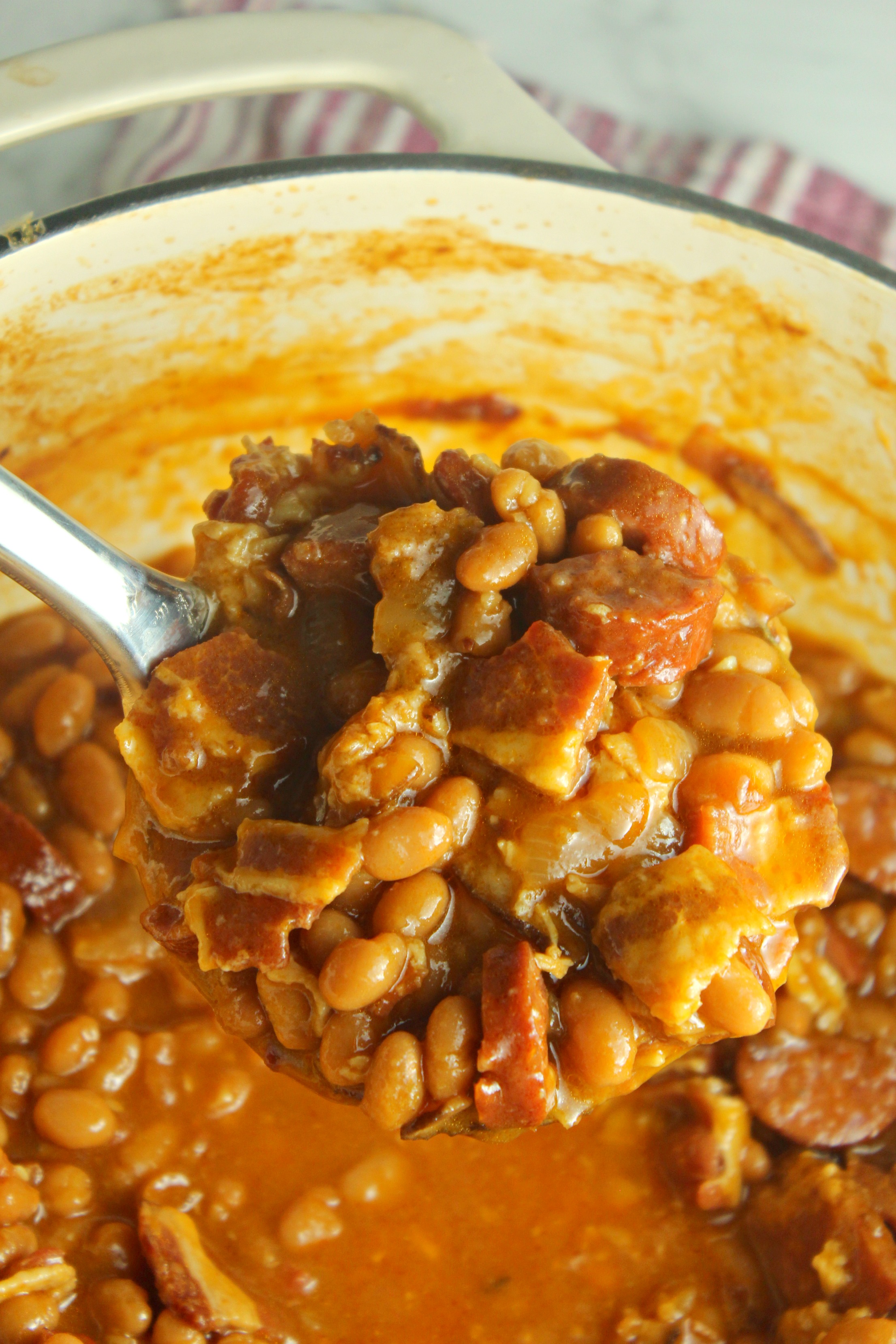 Ultimate Baked Beans with Smoked Sausage in a red dutch oven pot 