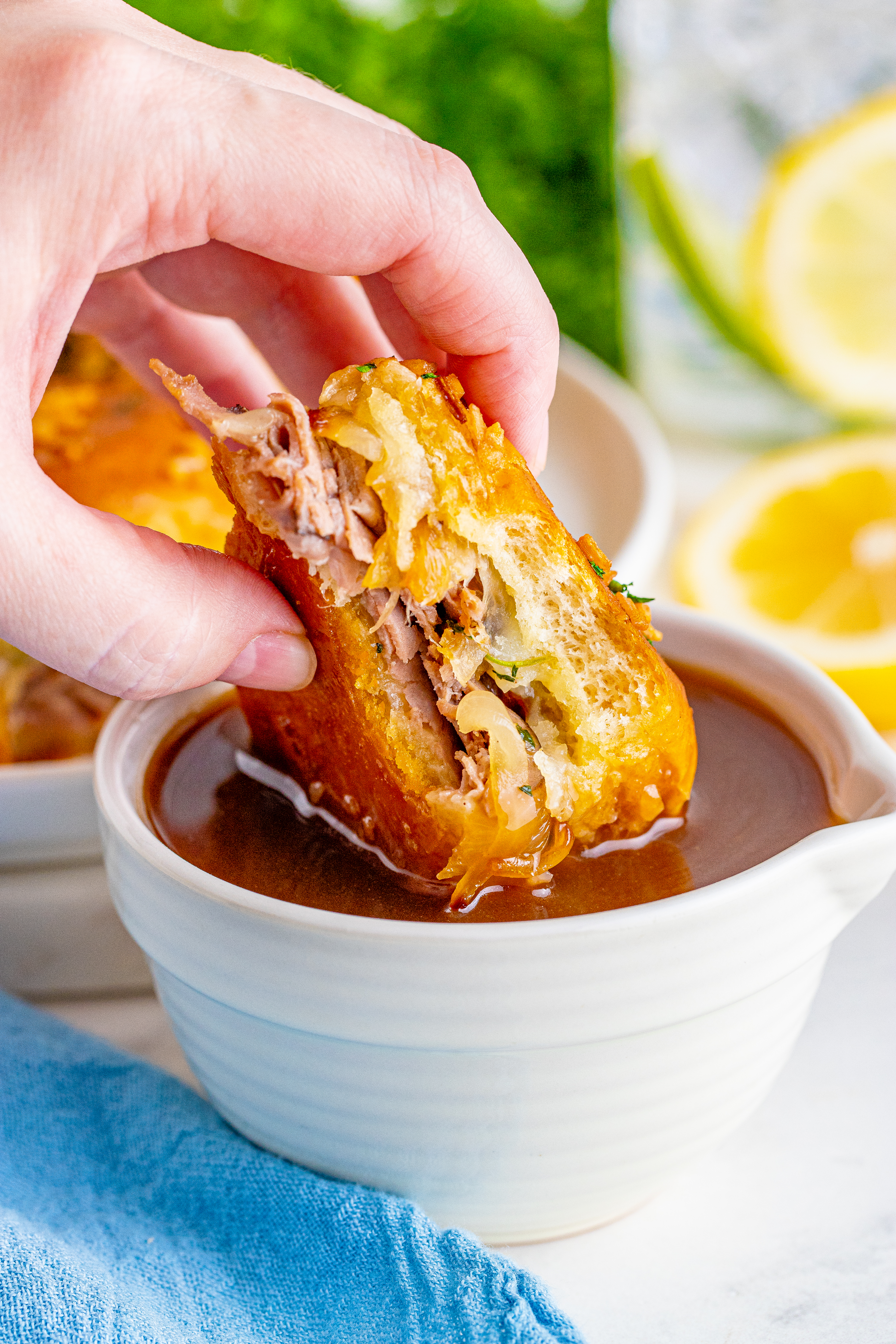 French Dip Sliders being dipped into a white bowl of Au Jus
