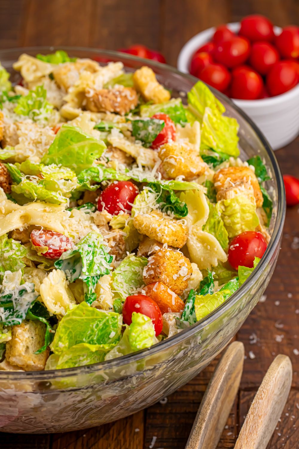 chicken caesar pasta salad in a bowl and a bowl of tomatoes behind it