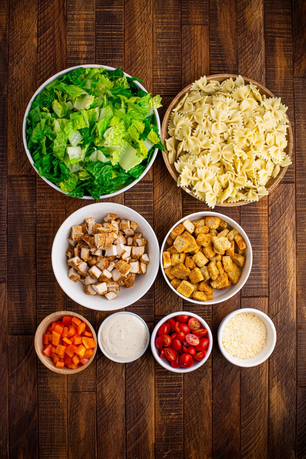 ingredients for Chicken Caesar Pasta Salad in single serve bowls on table 