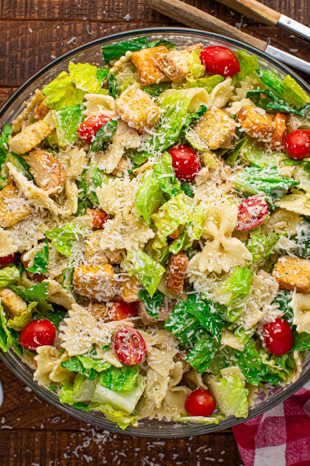 Chicken Caesar Pasta Salad in a bowl with tongs to the side of it on table 