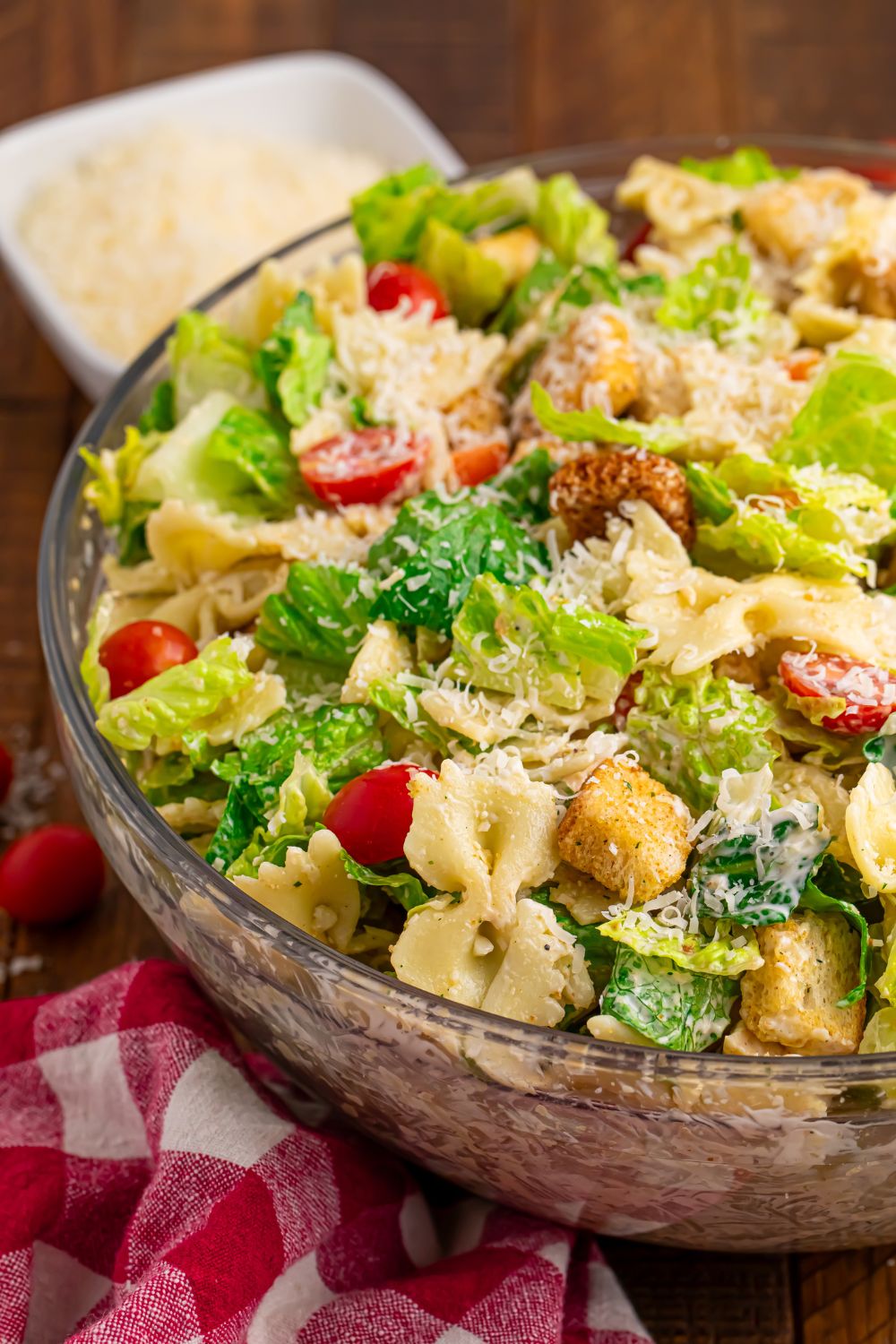 Chicken Caesar Pasta Salad in a bowl sitting on table with a red checkered towel under bowl 