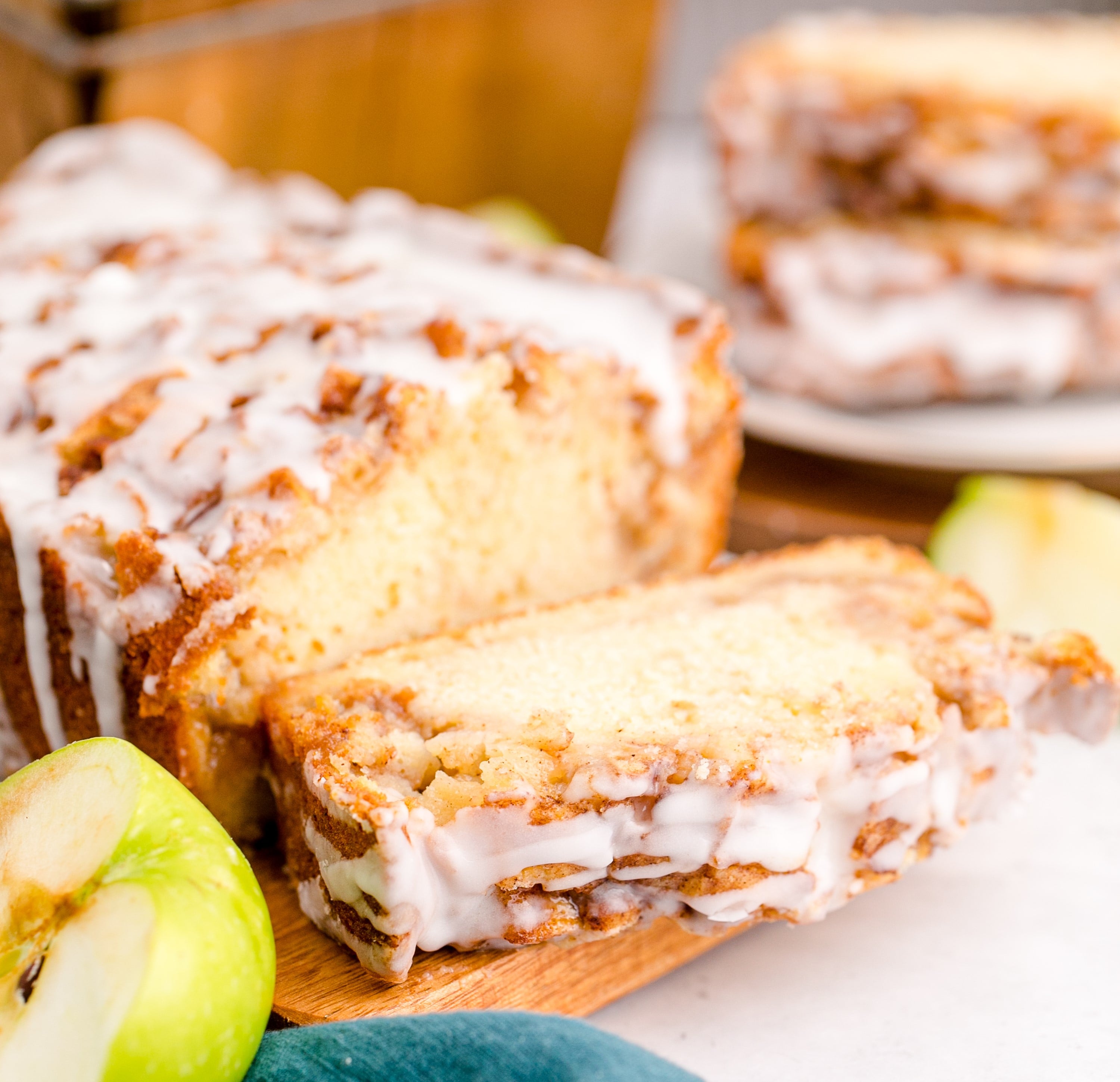 Apple Bread sliced on a cutting board with icing dripping