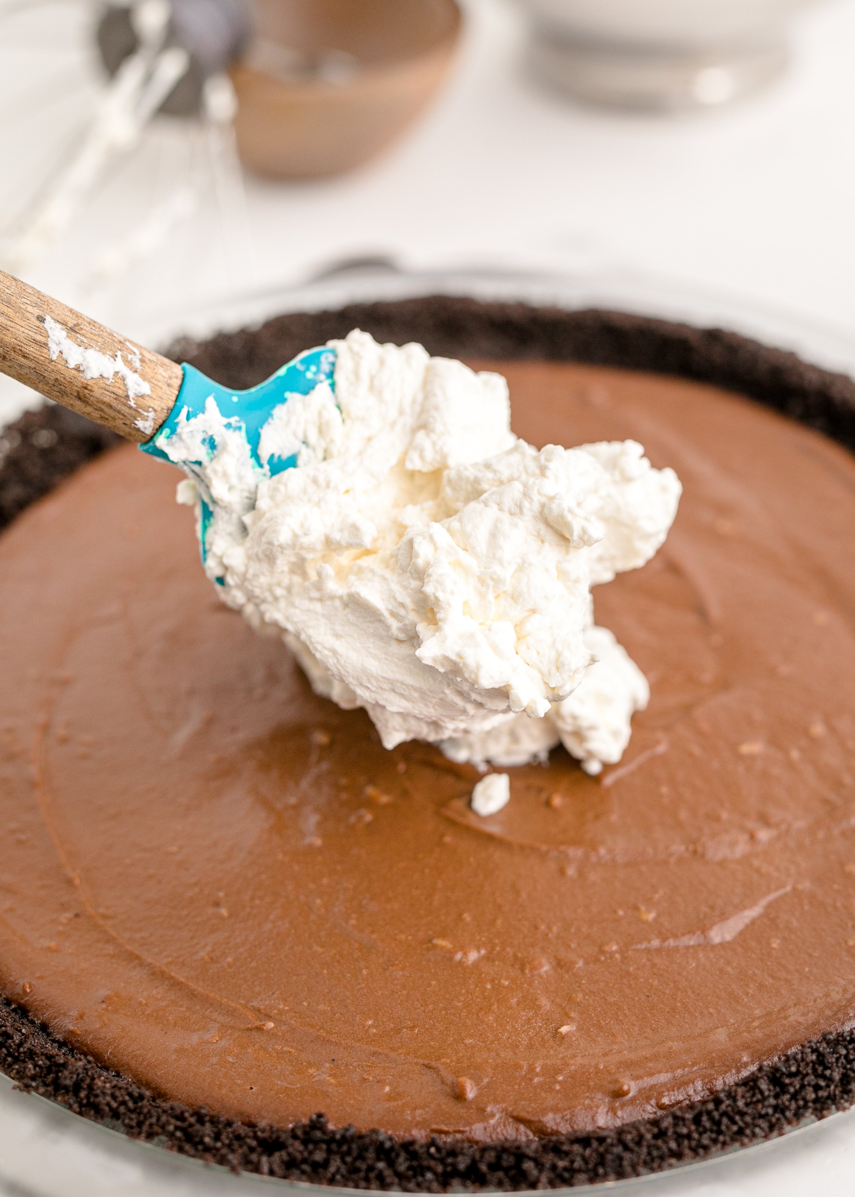 Chocolate Cream Pie with a spoon dropping the whipped cream on top