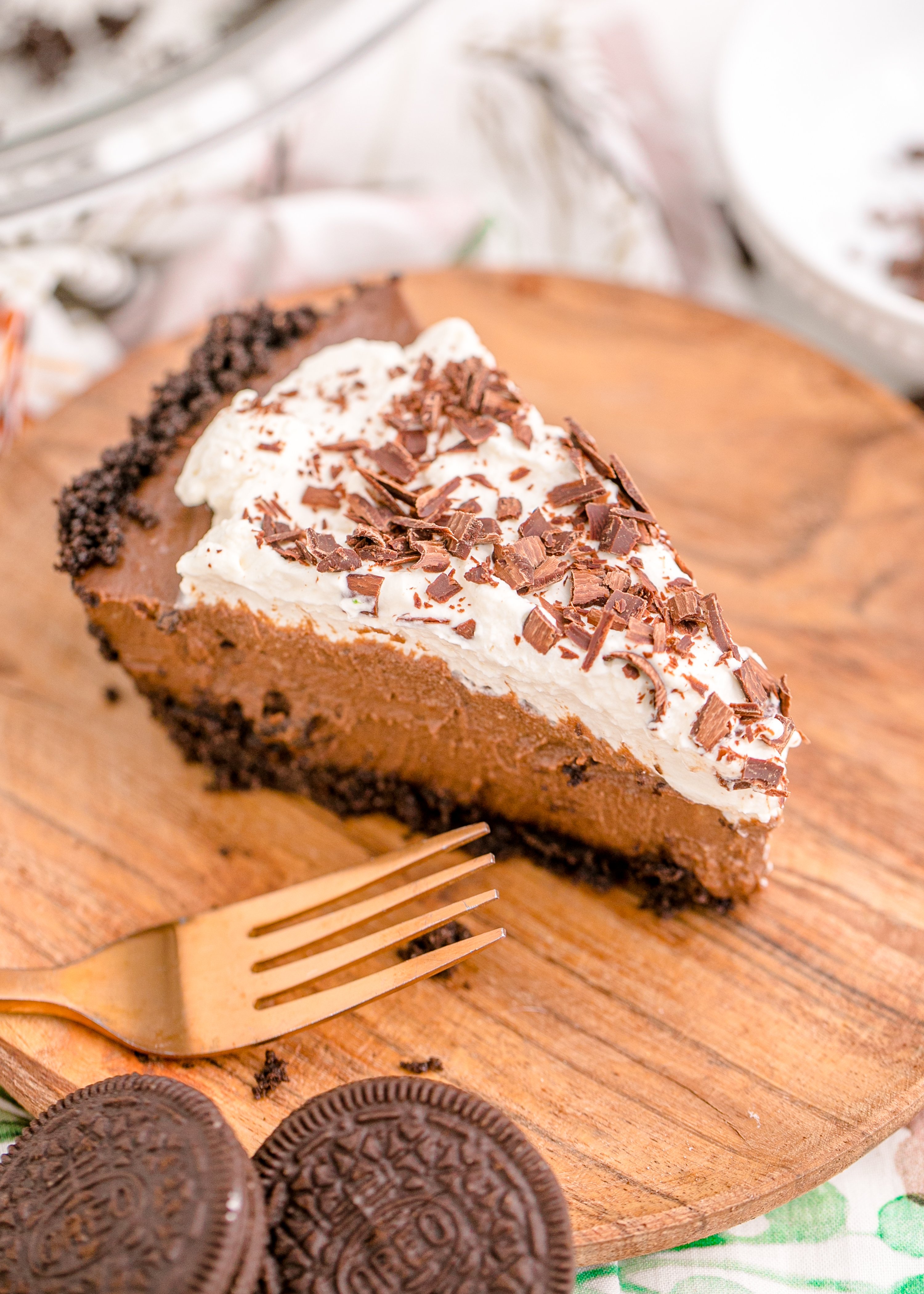 Chocolate Cream Pie topped with whipped cream and chocolate shavings on a brown cutting board