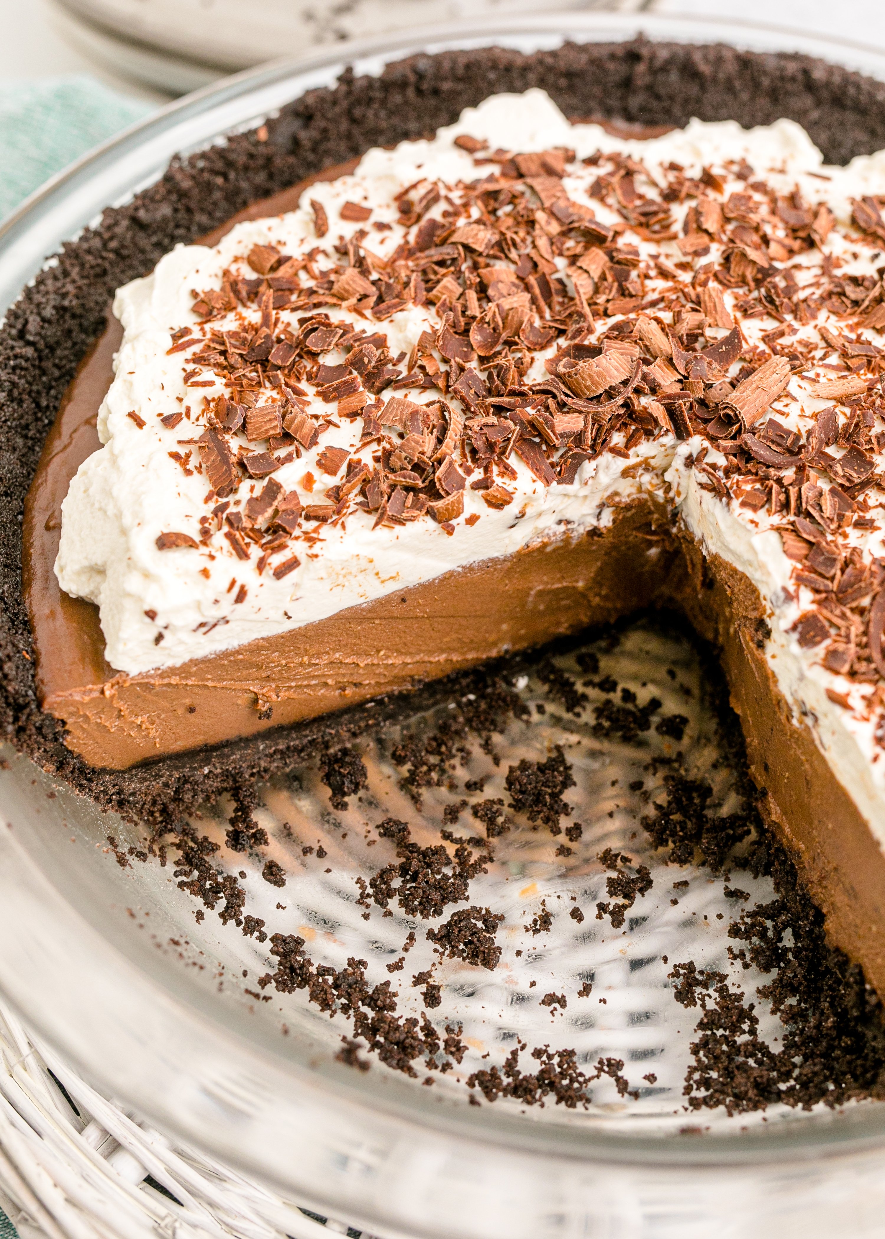 Chocolate Cream Pie topped with whipped cream and chocolate shavings in a white pie dish with a slice taken out