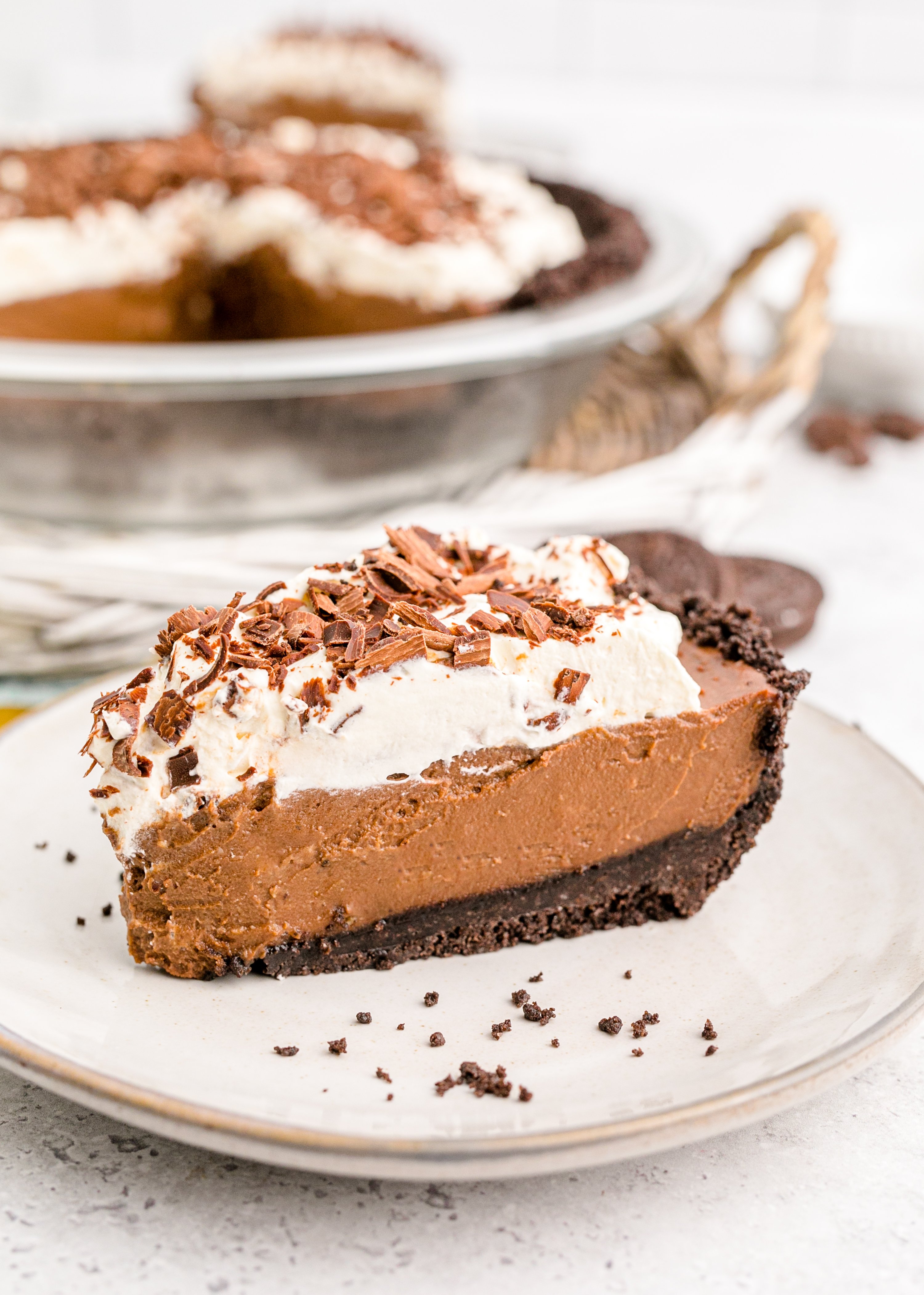 Chocolate Cream Pie topped with whipped cream and chocolate shavings on a white plate