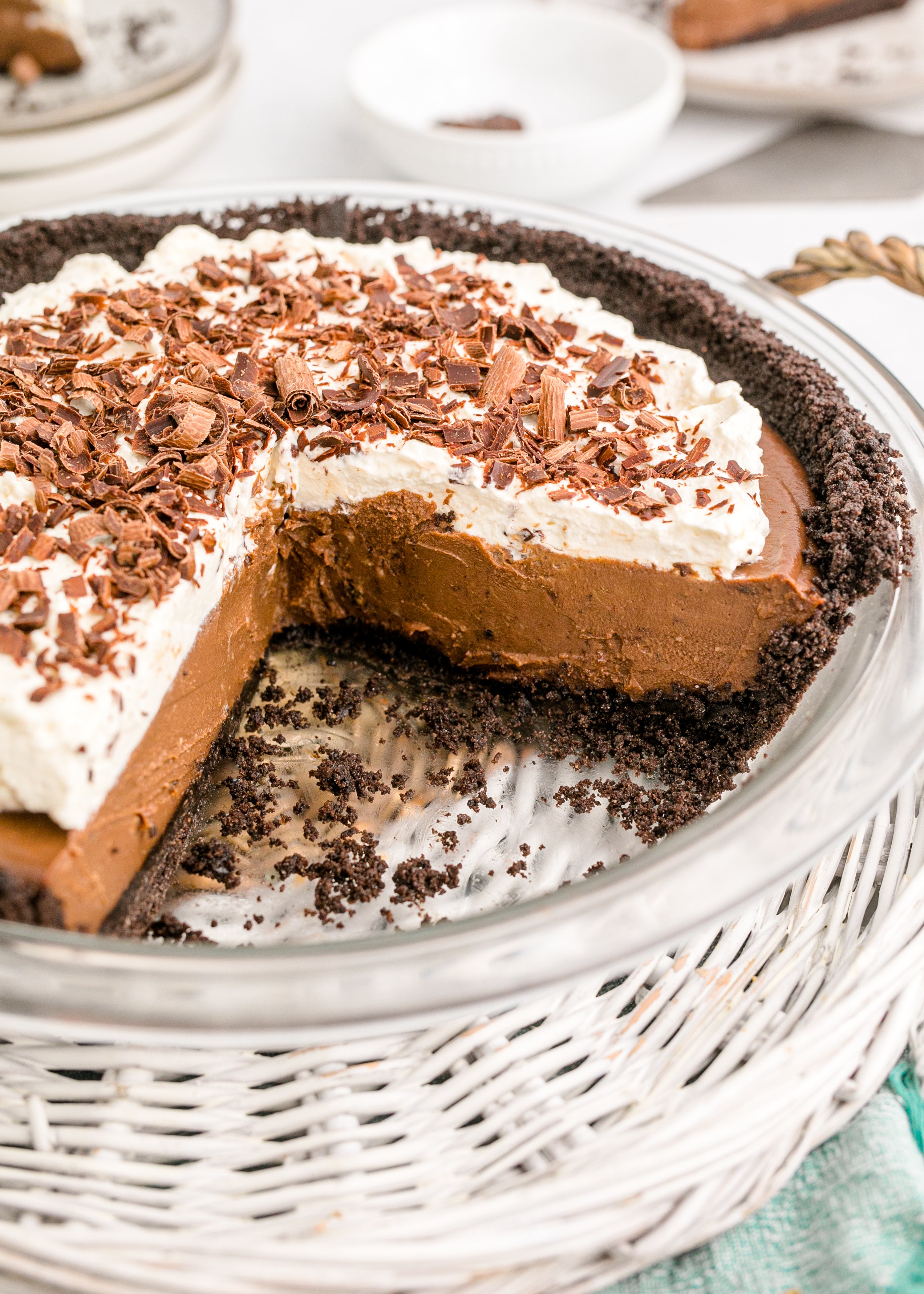 Chocolate Cream Pie topped with whipped cream and chocolate shavings in a white pie dish with a slice taken out