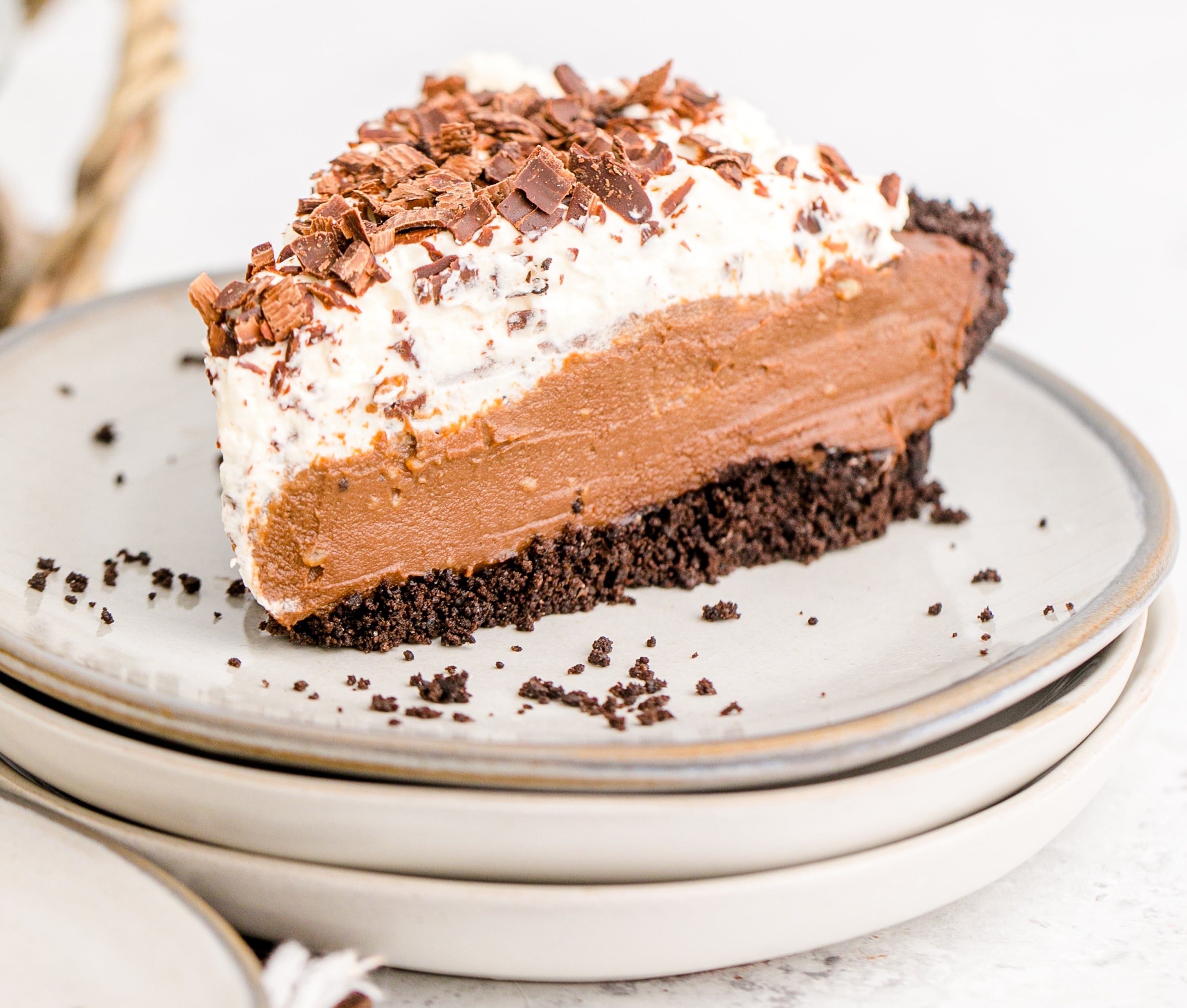 Chocolate Cream Pie topped with whipped cream and chocolate shavings on a white plate