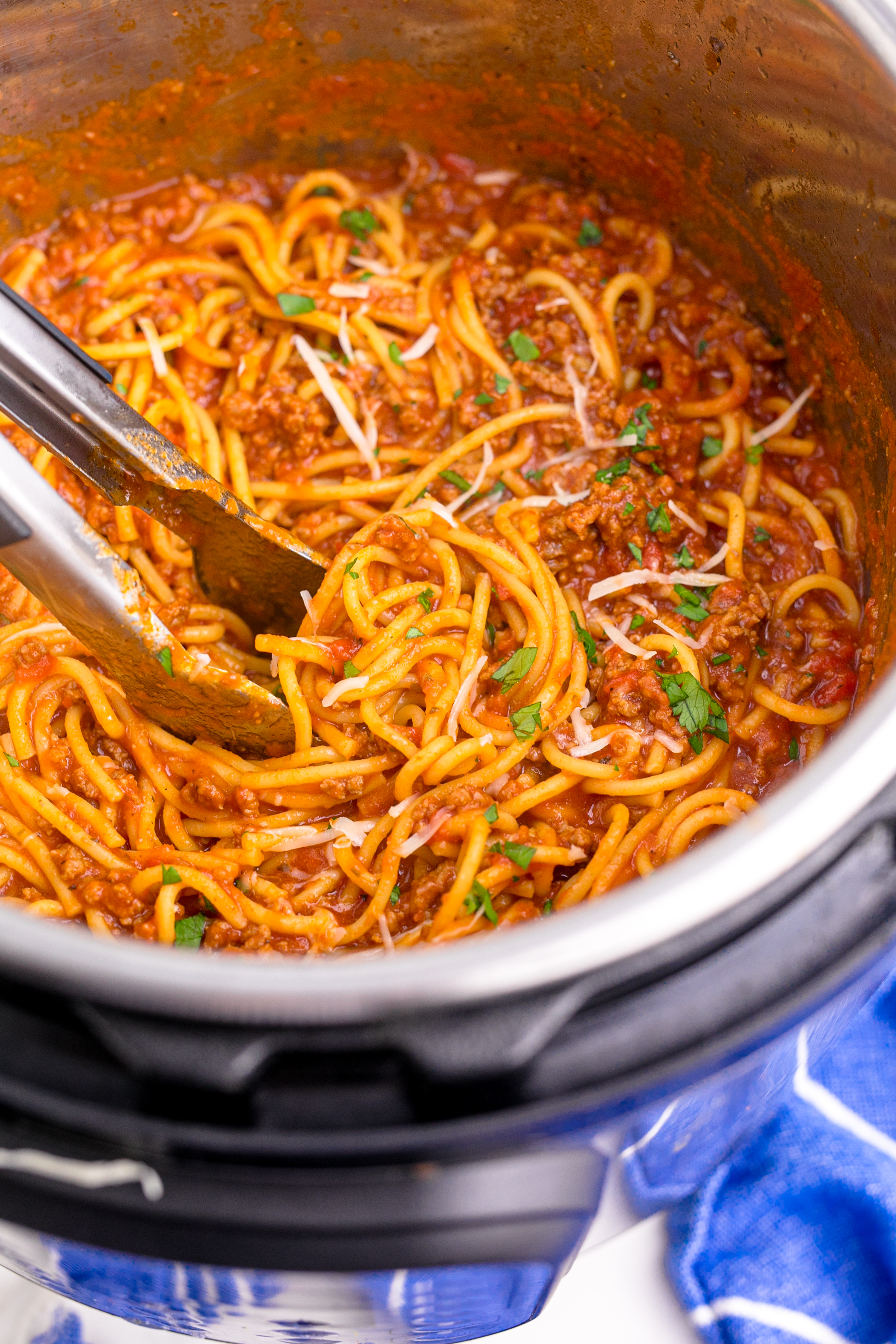 Instant Pot Spaghetti inthe instant pot being mixed with tongs covered in parmesan cheese