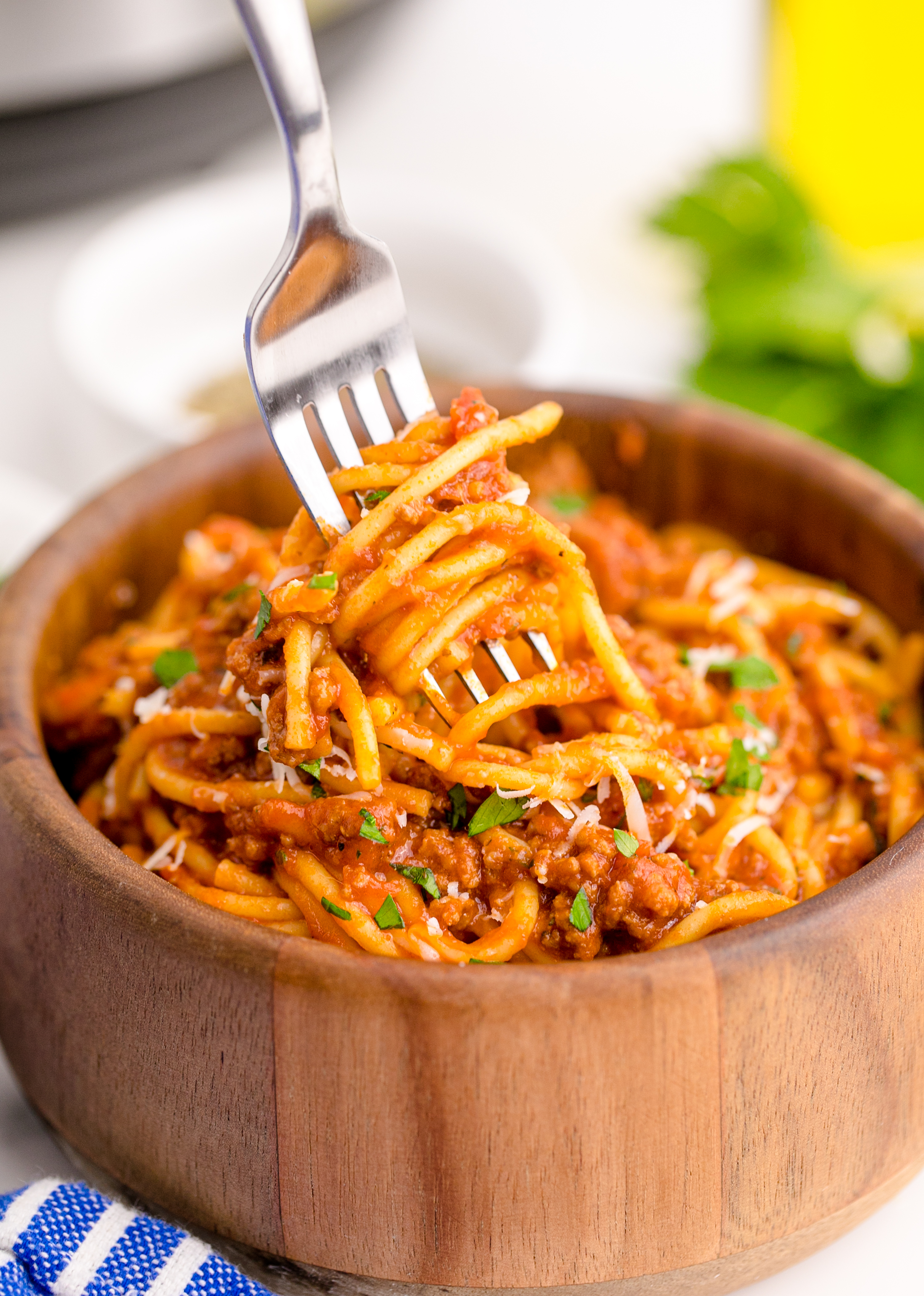 Instant Pot Spaghetti in a wooden bowl with a fork lifting the spaghetti up