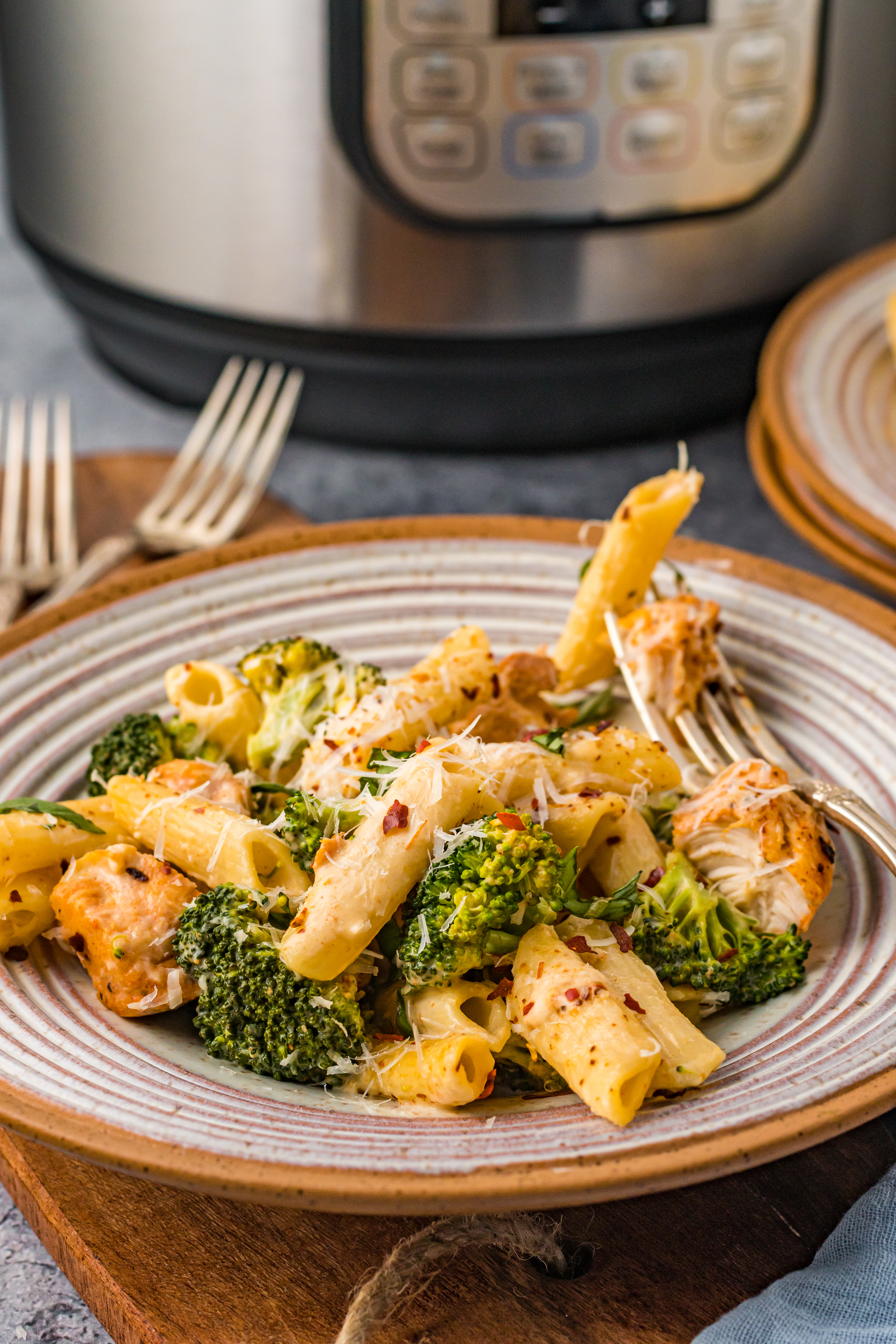 Chicken Pasta on a plate covered in cheese with an instant pot in the background