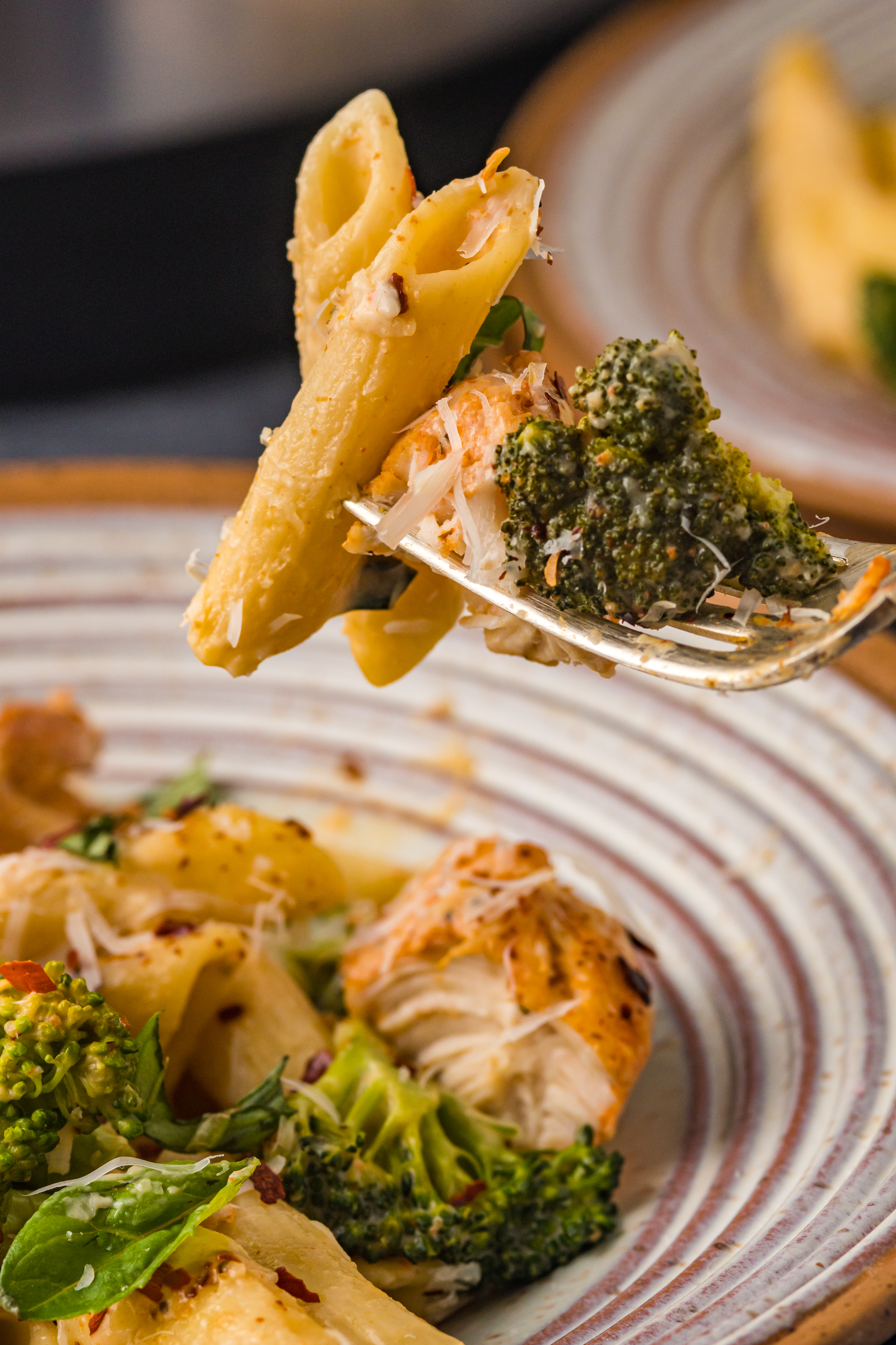 Chicken Pasta on a plate covered in cheese on a fork being lifted