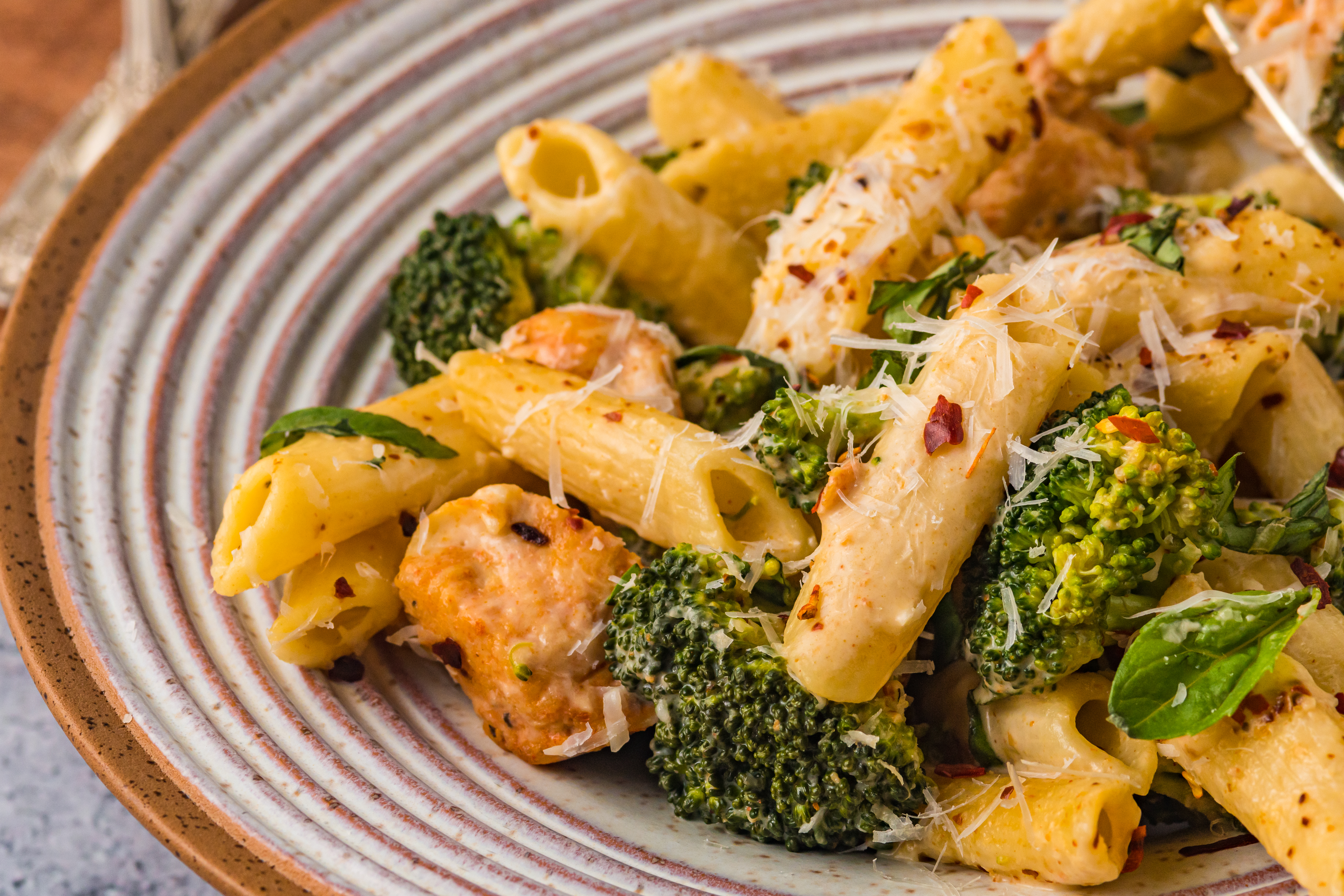 Chicken Pasta on a plate covered in cheese with broccoli