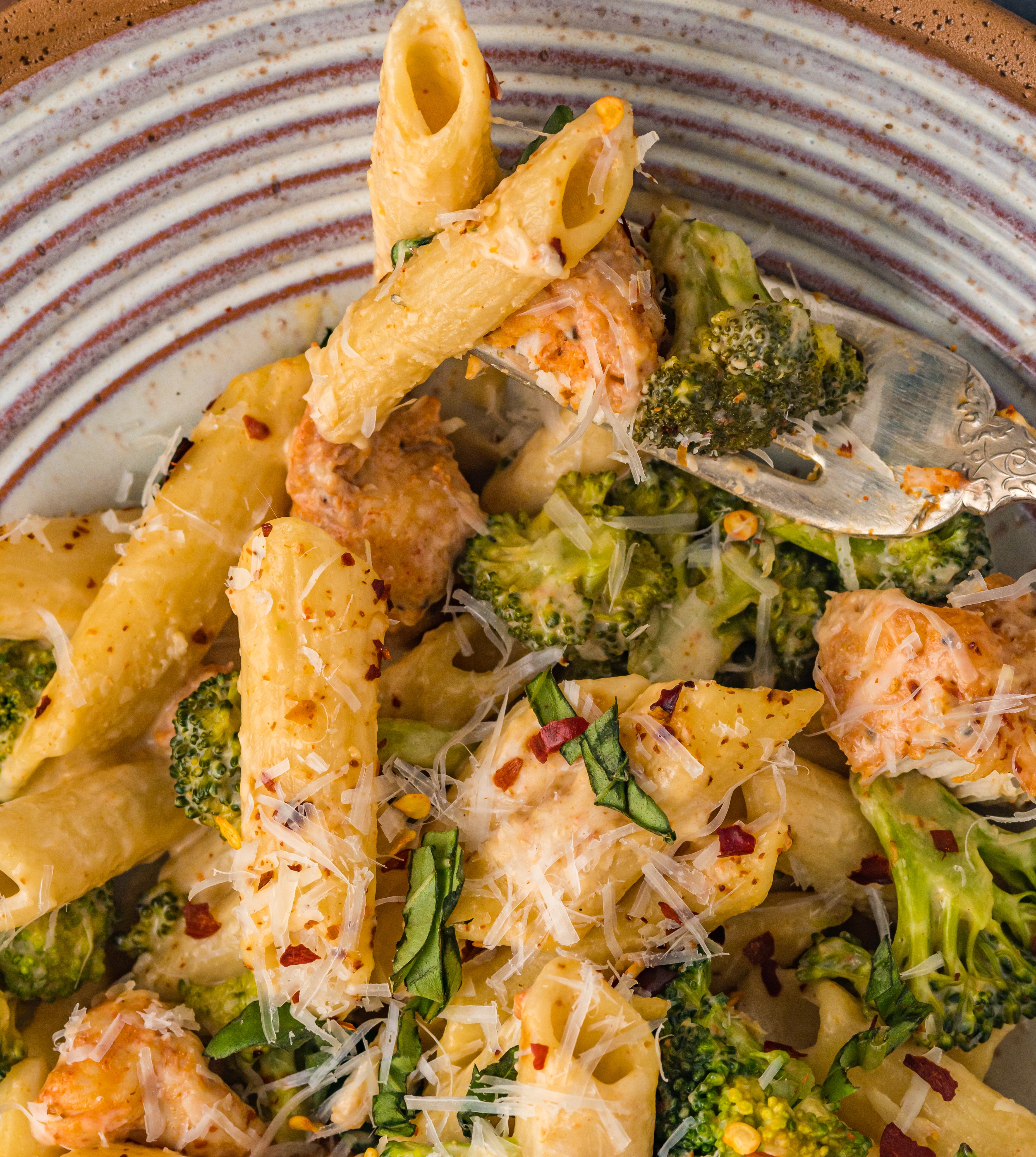 Chicken Pasta on a plate covered in cheese with broccoli