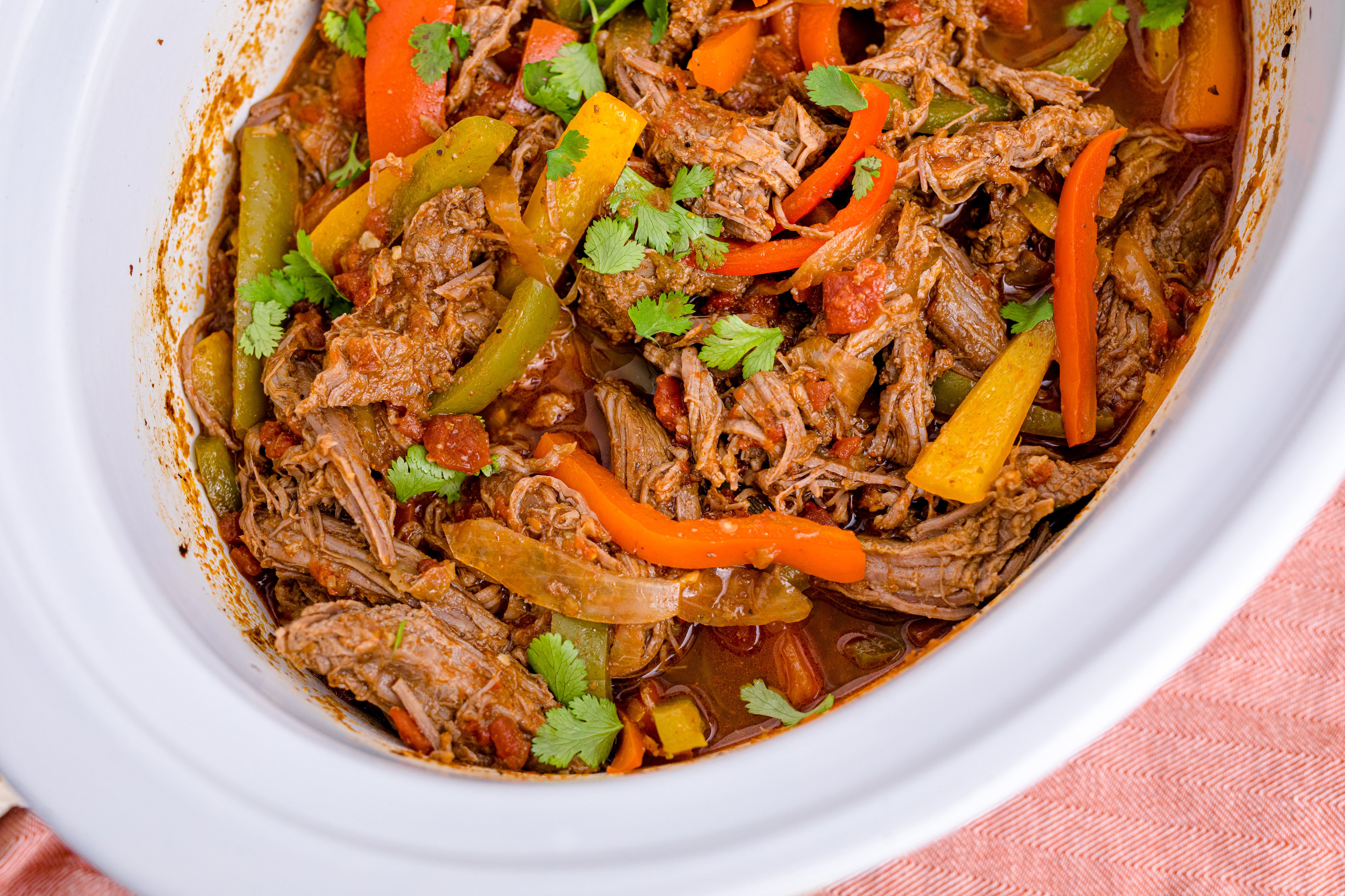 Steak Fajitas in a white crockpit with red and green peppers mixed in