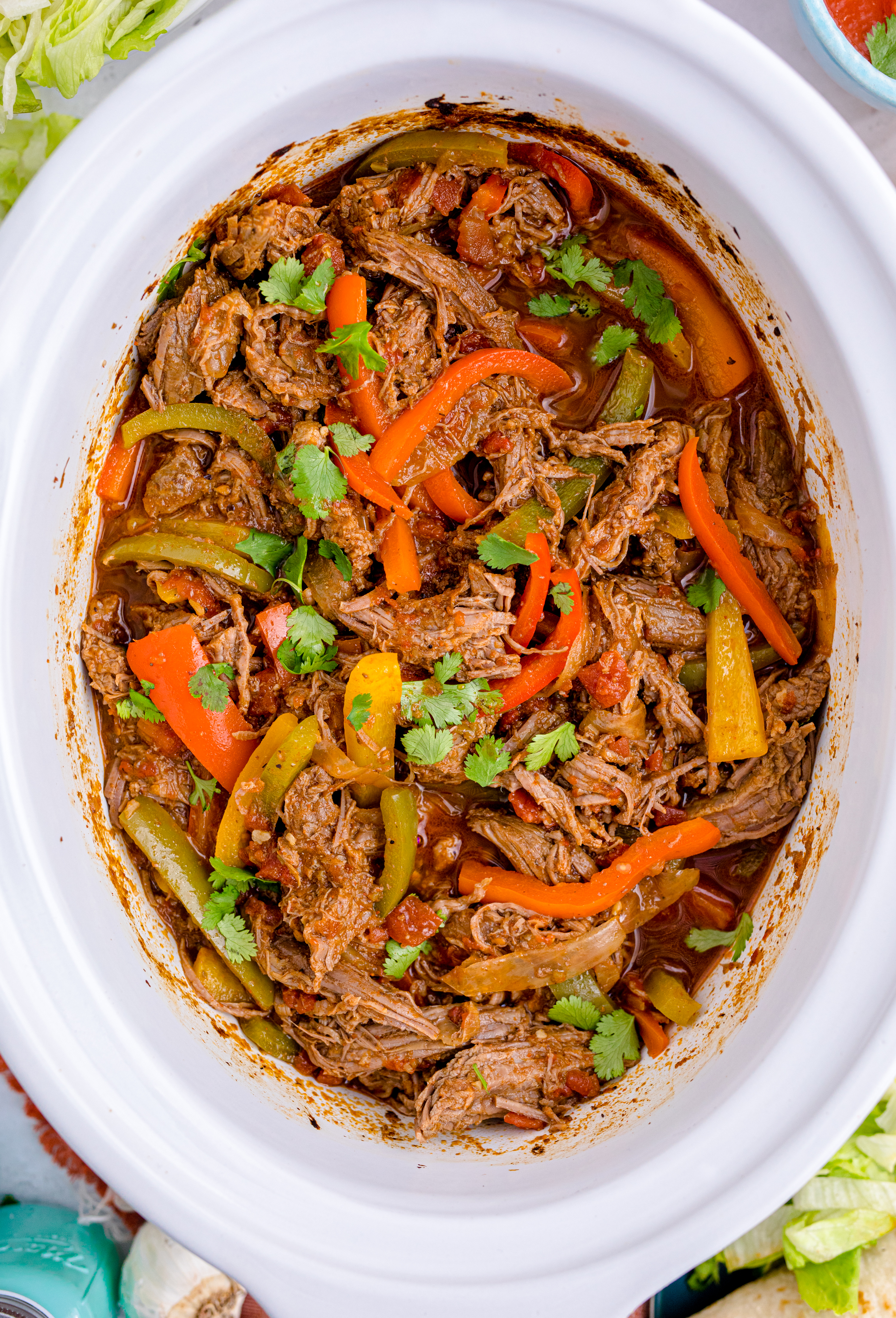Steak Fajitas in a white crockpit with red and green peppers mixed in