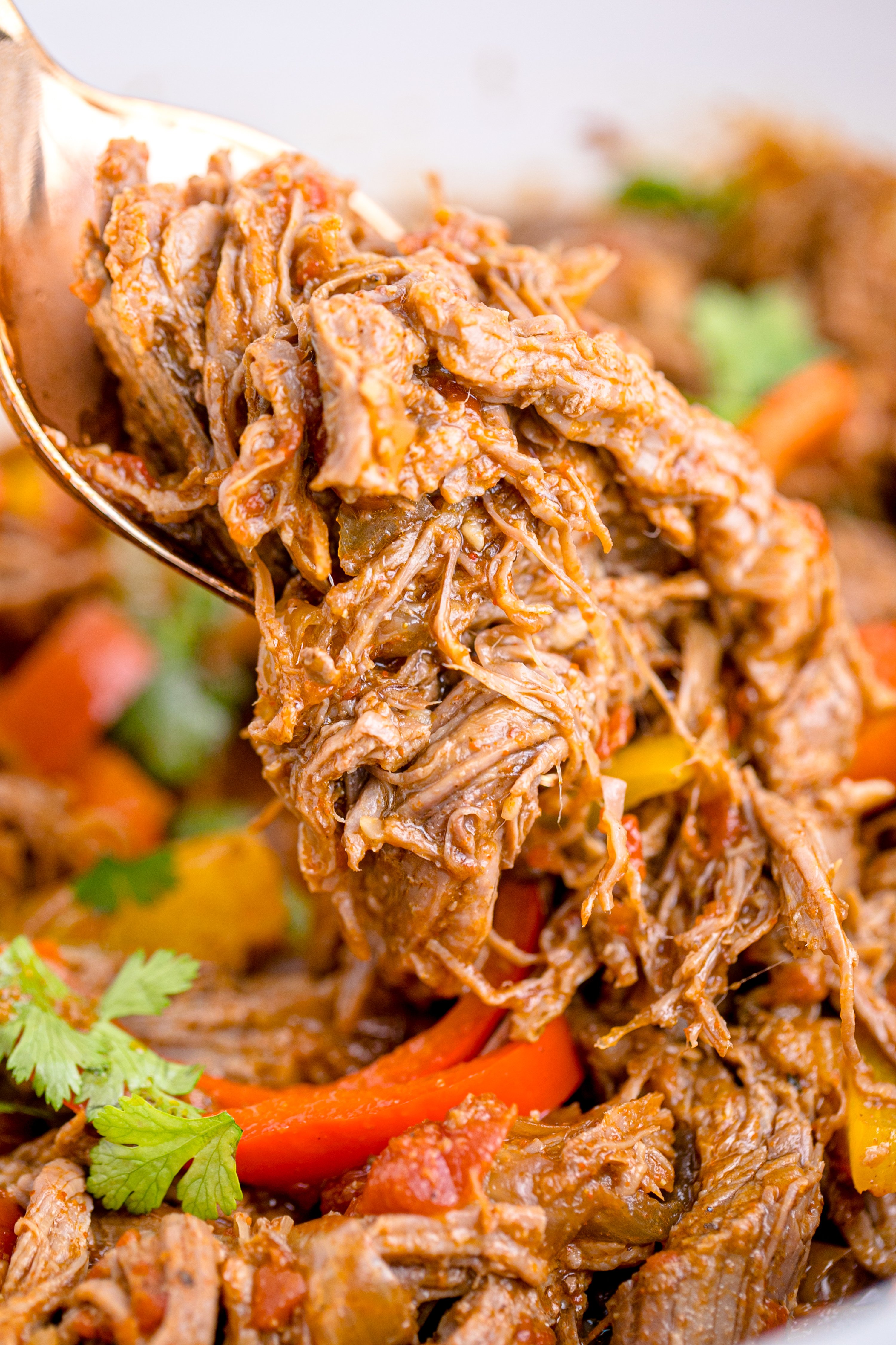 Steak Fajitas in a white crock pot being lifted with a spoon