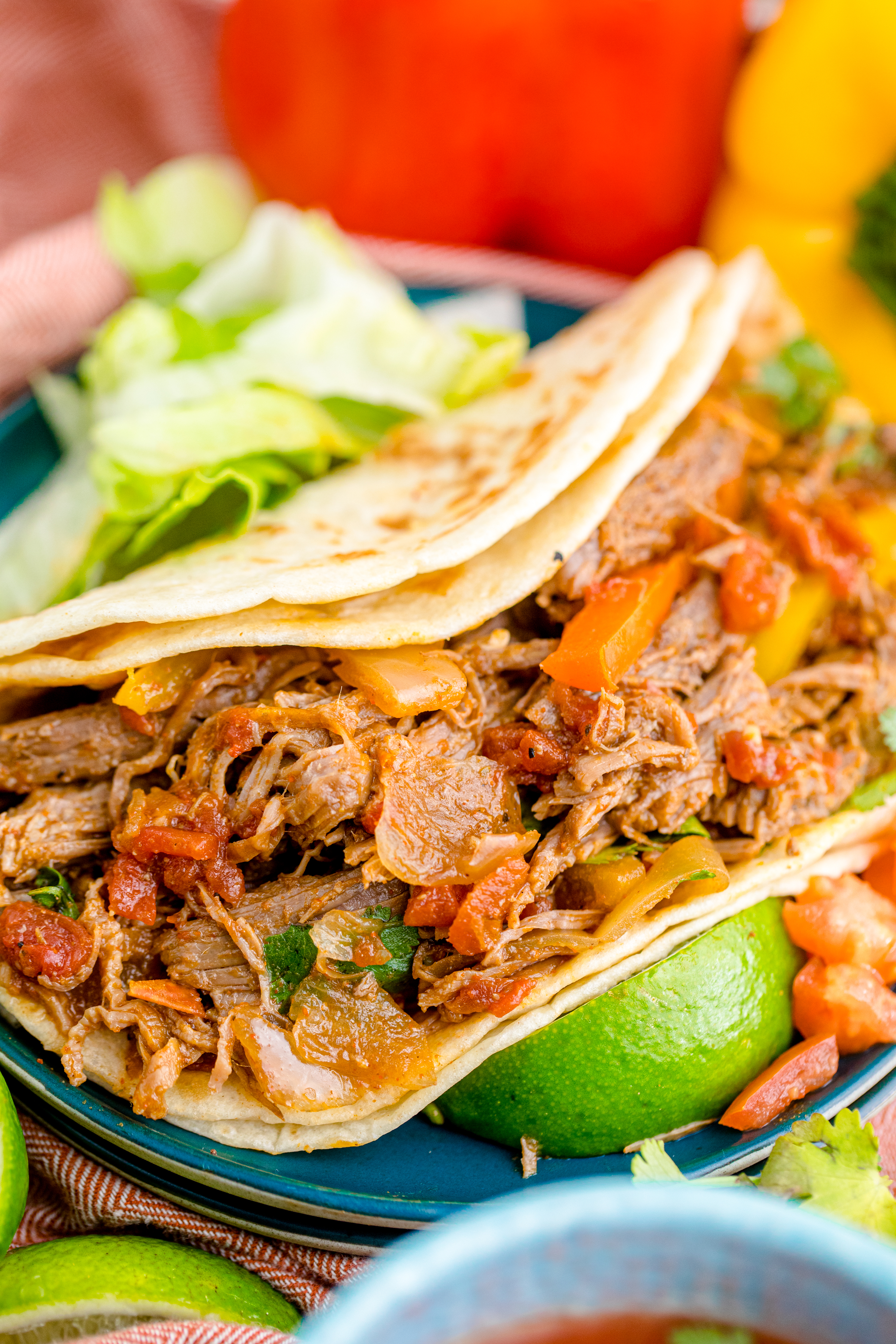 Steak Fajitas wrapped in a tortilla with lettuce piled next to it and limes with salsa