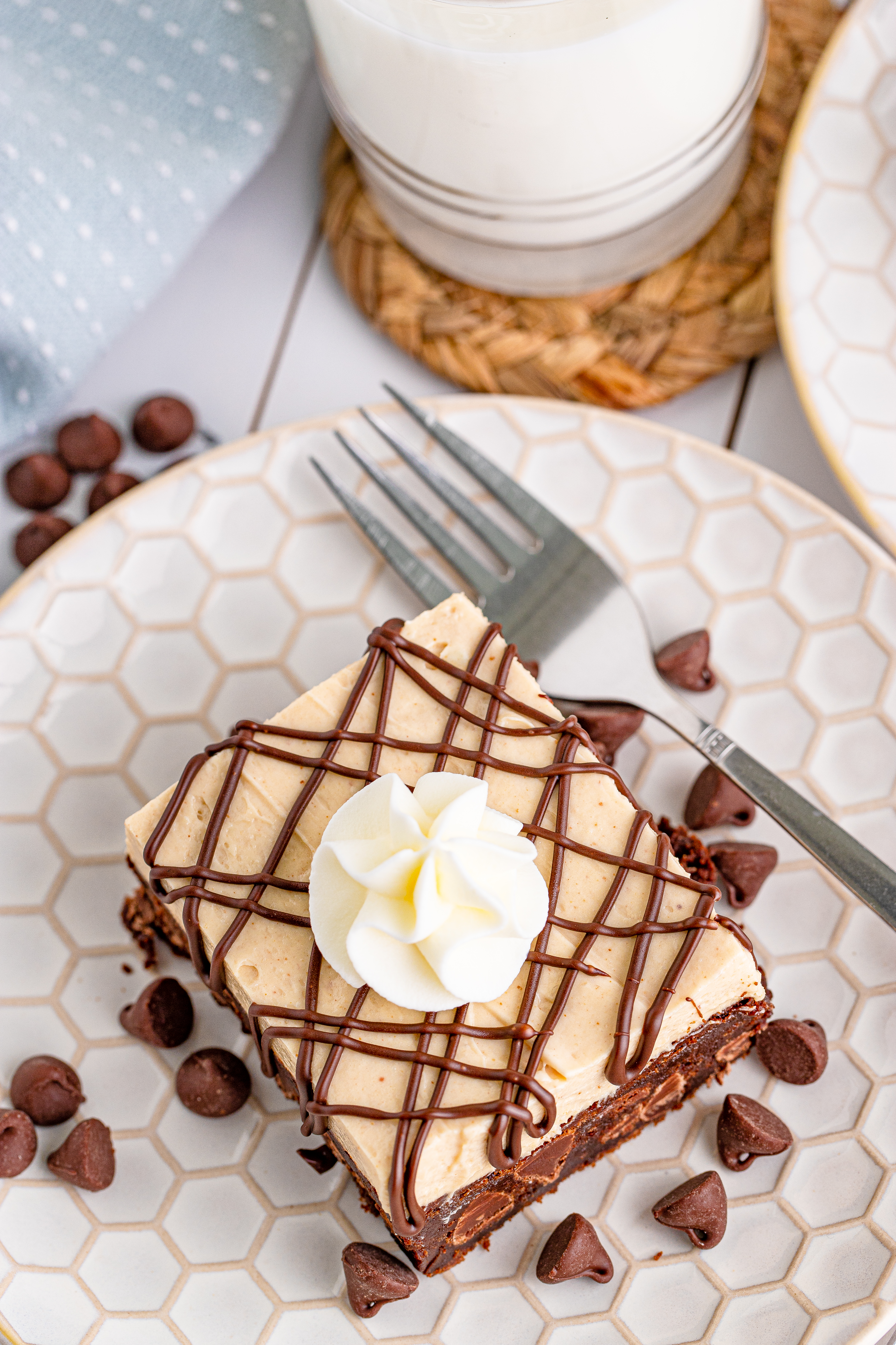 overhead shot of Peanut Butter Brownies on a white place drizzled with chocolate and topped with whipped cream