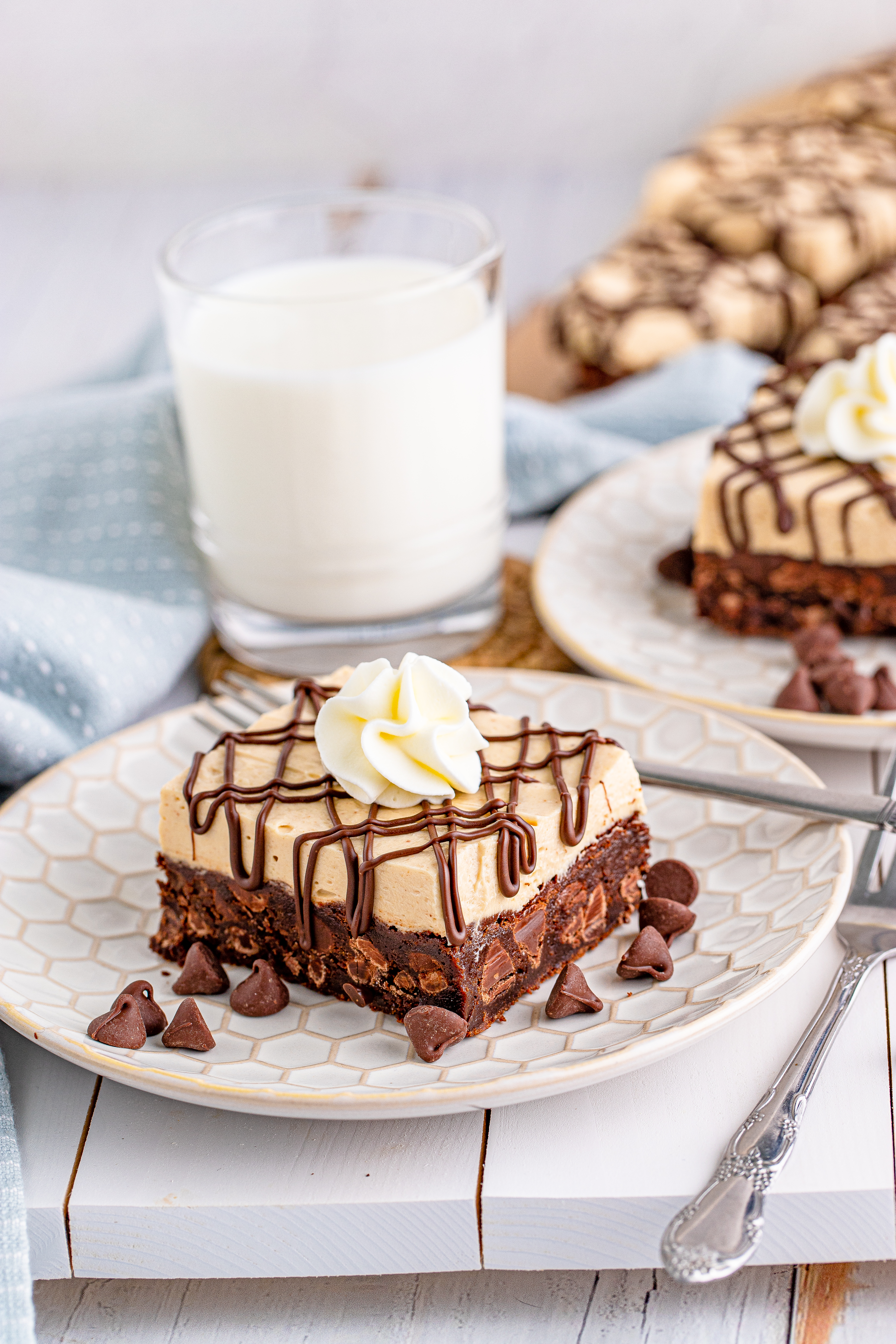 Peanut Butter Brownies on a white place drizzeled with chocolate and topped with whipped cream