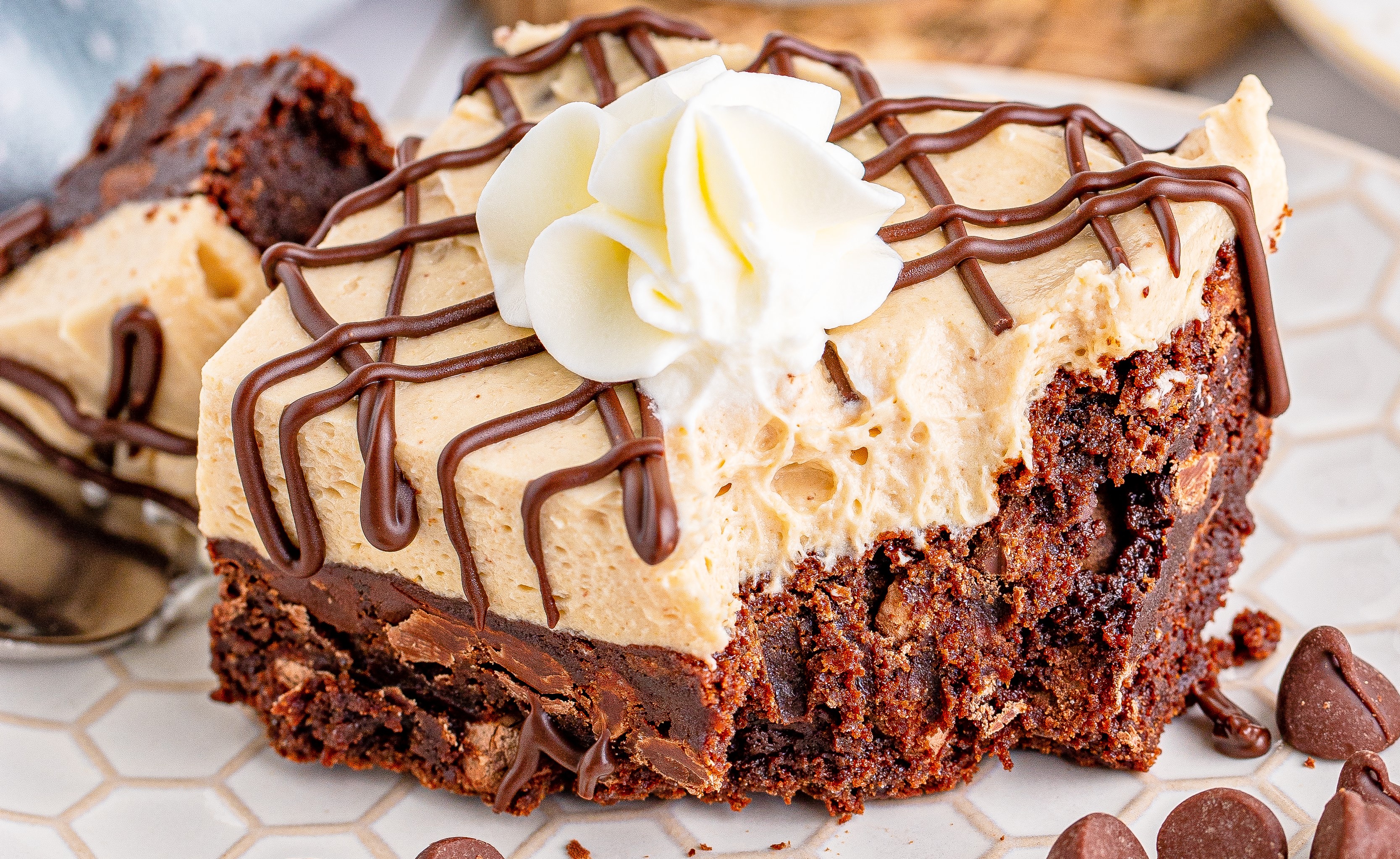Peanut Butter Brownies on a white place drizzeled with chocolate and topped with whipped cream