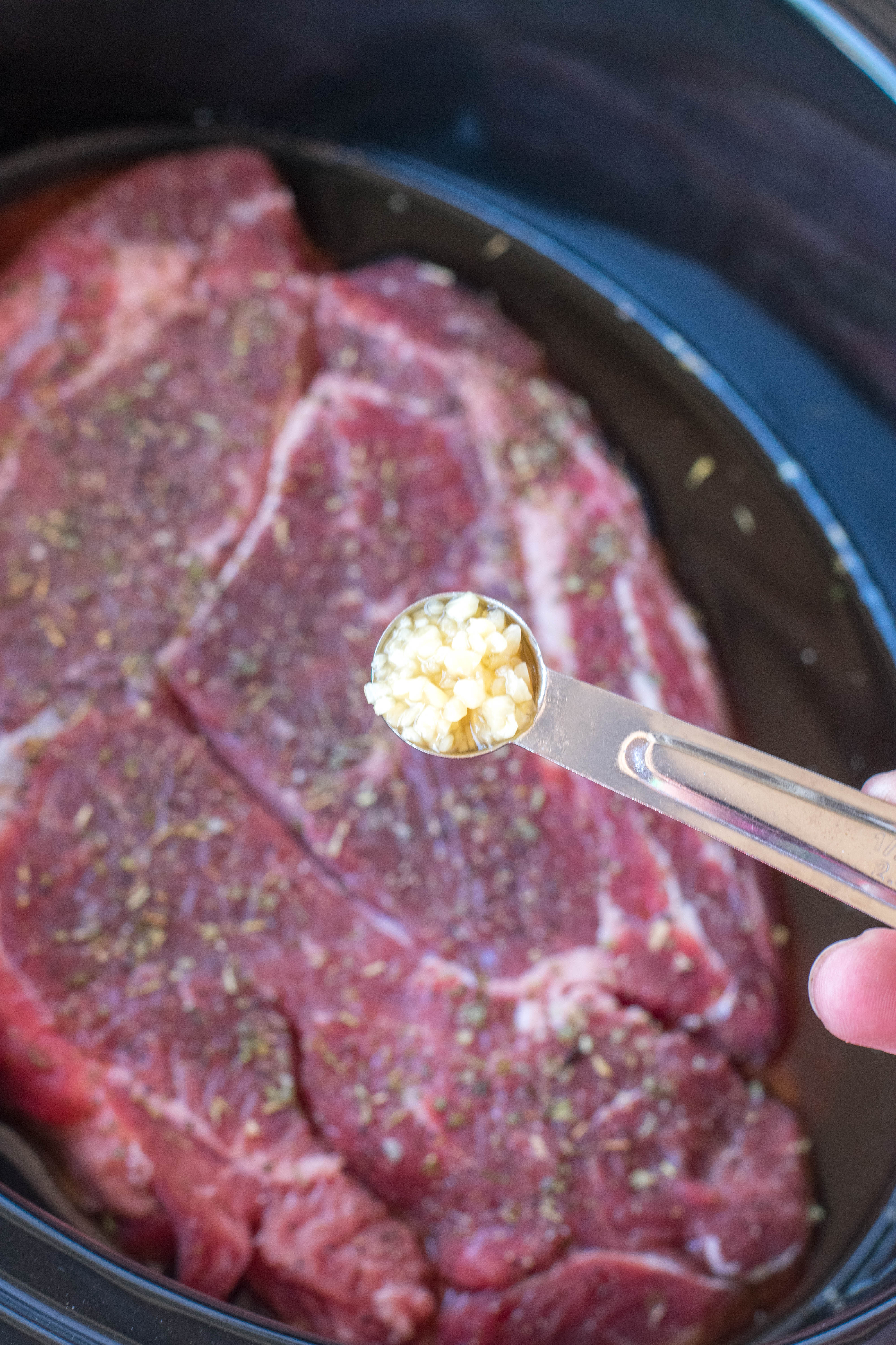 crock pot chuck roast in a black crock pot uncooked