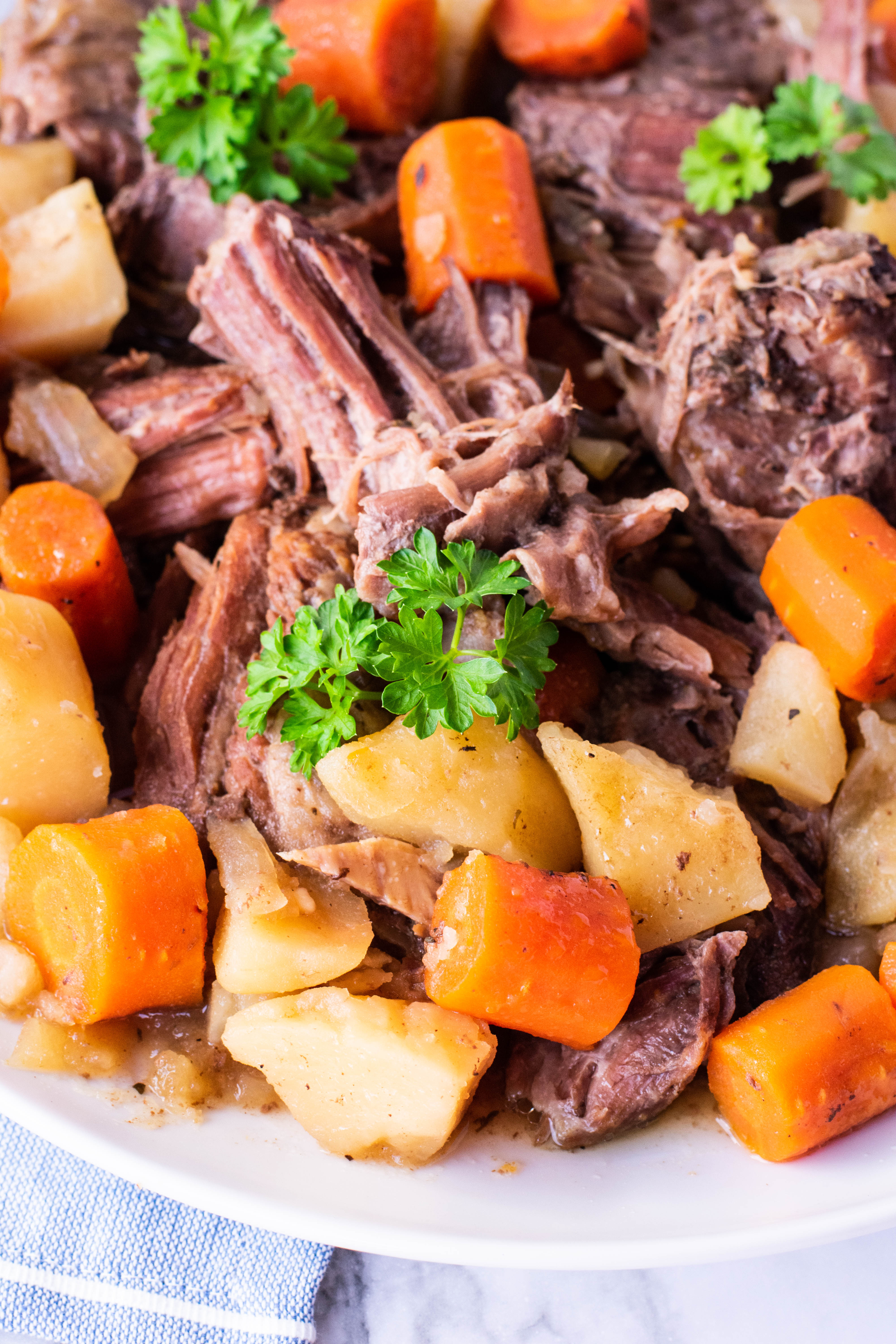 crock pot chuck roast on a plate with potatoes and carrots close up shot