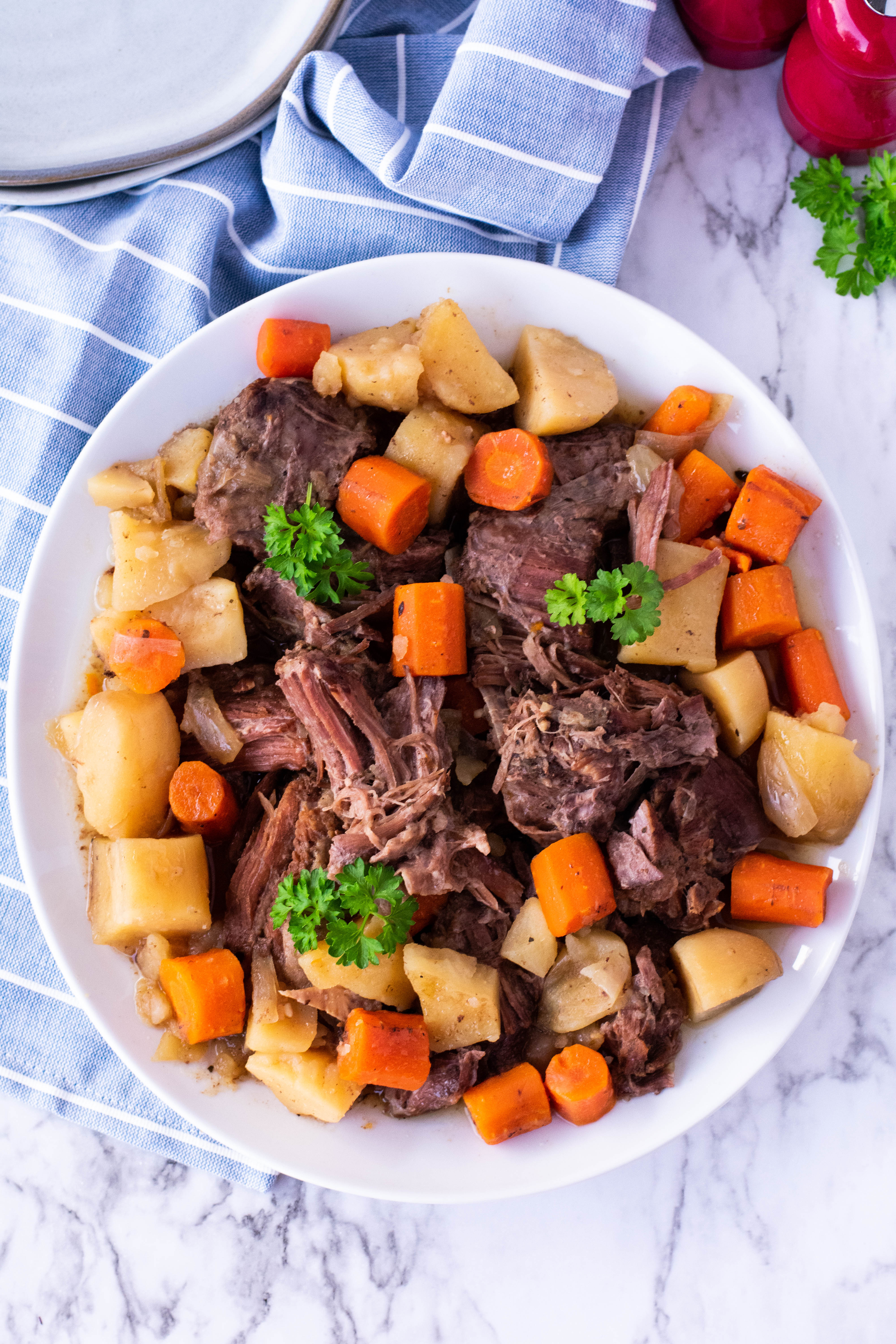 crock pot chuck roast on a plate with potatoes and carrots overhead shot