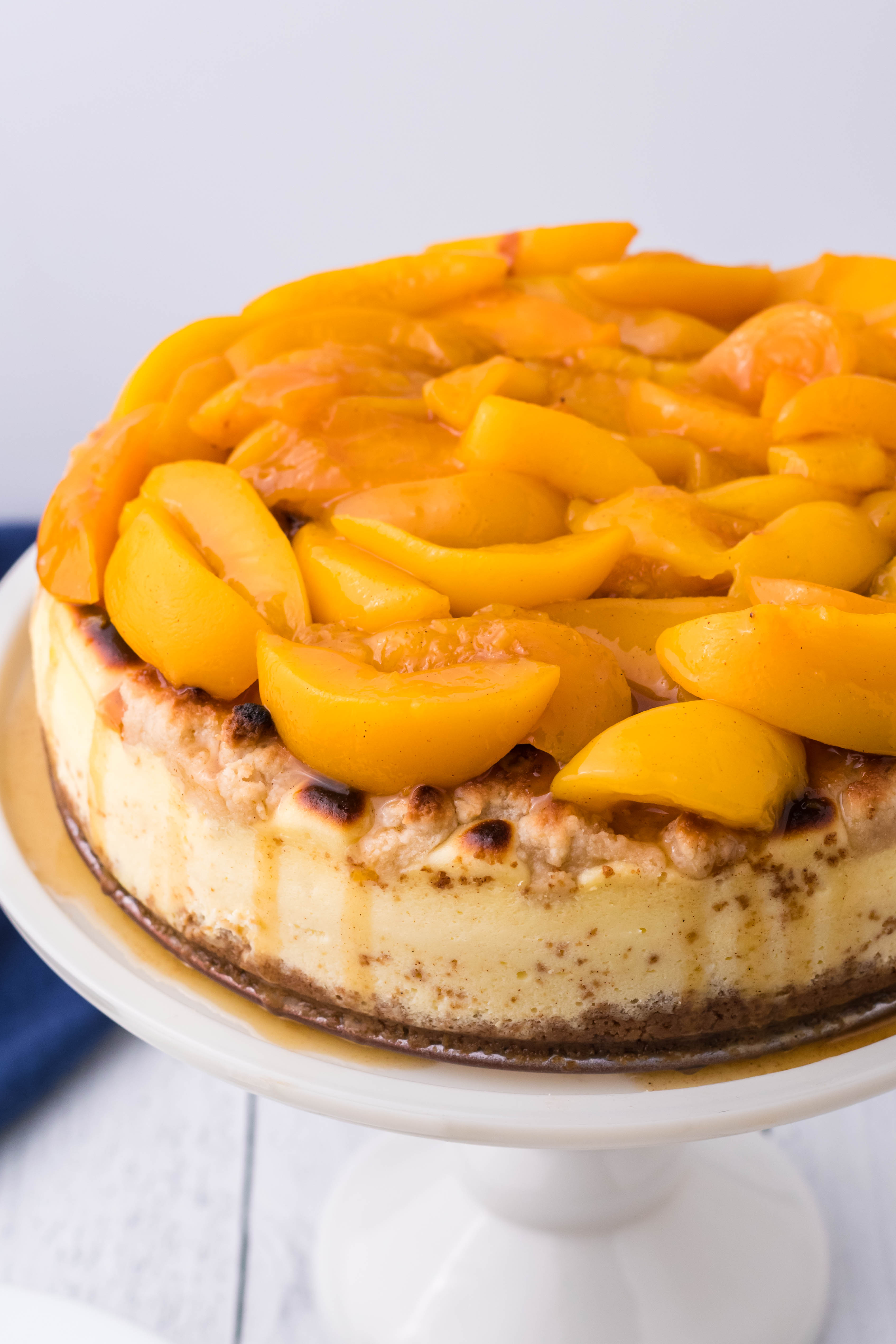 Peach Cobbler Cheesecake on a white cake stand overhead shot