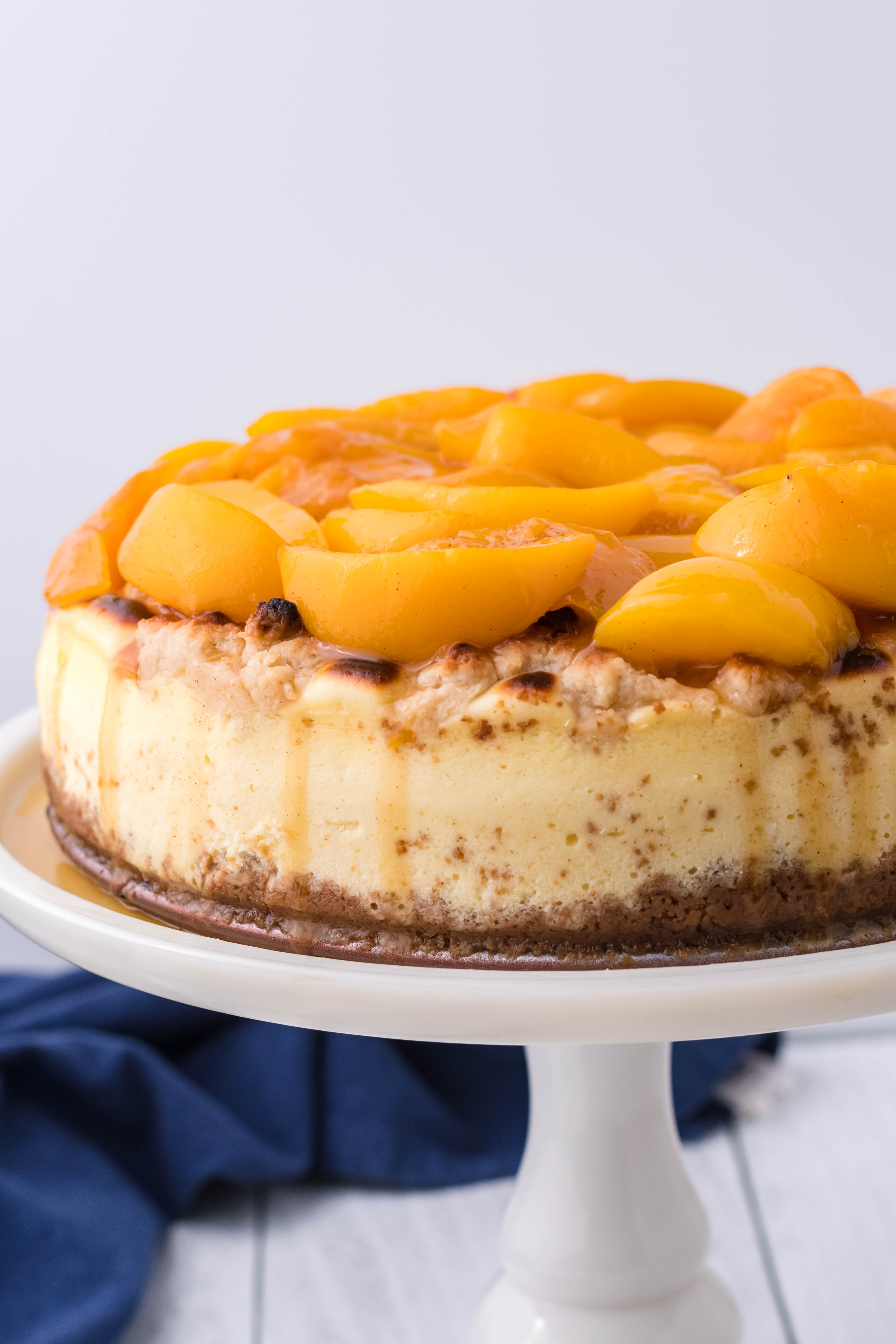 Peach Cobbler Cheesecake on a white cake stand