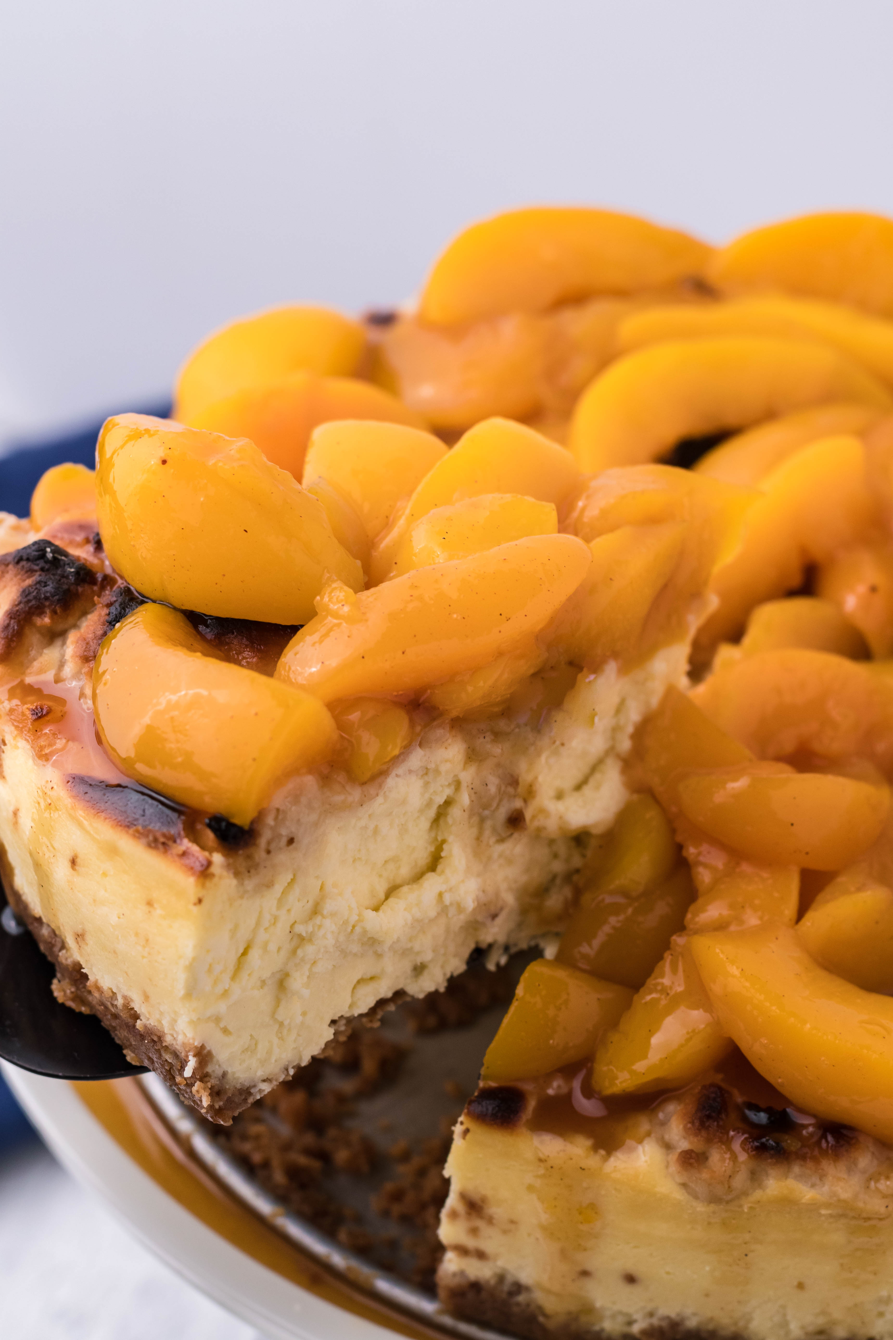 Peach Cobbler Cheesecake with a slice being lifted out on a spatula
