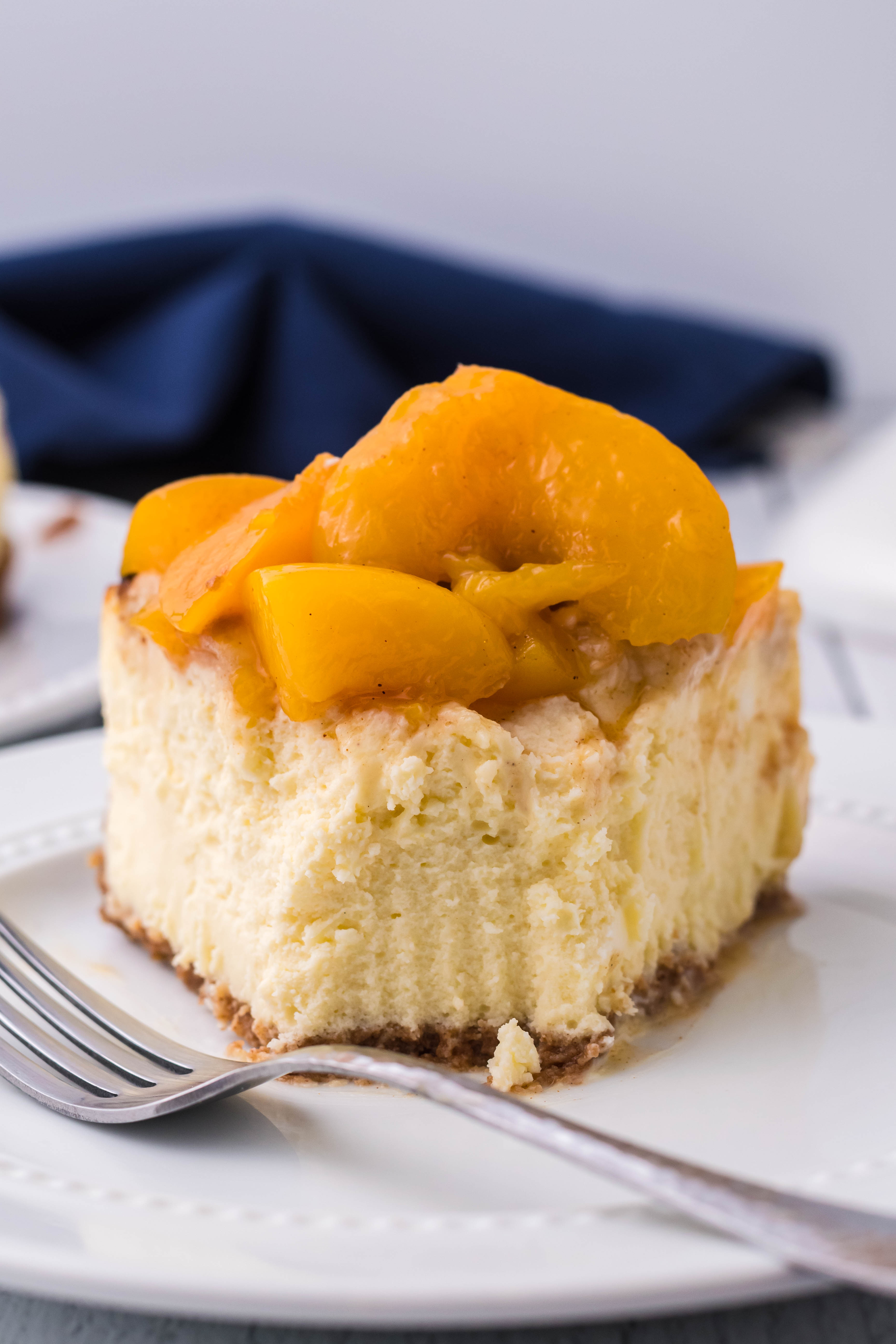 Peach Cobbler Cheesecake on a white plate with a bite taken out of the slice