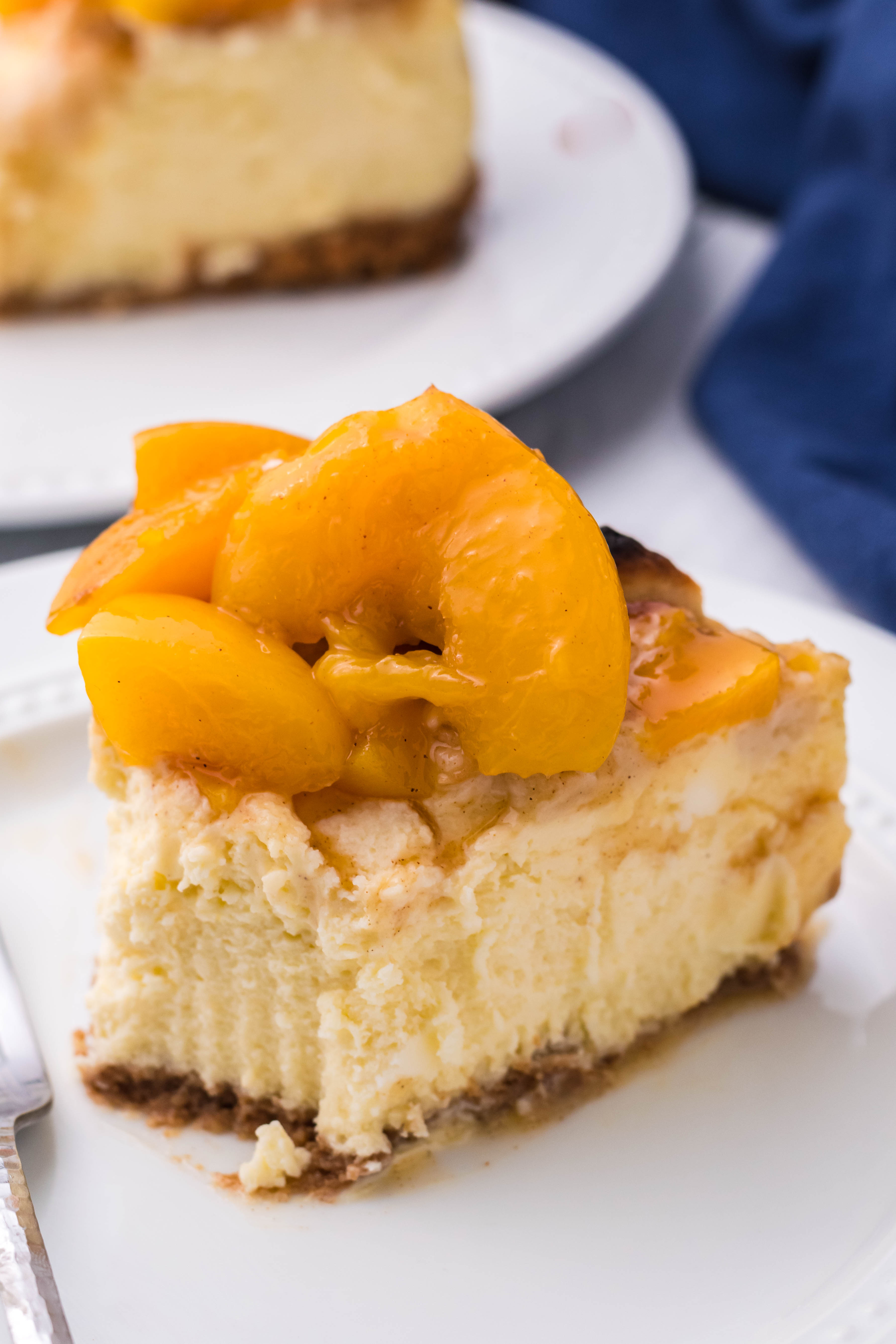 Peach Cobbler Cheesecake on a white plate with a bite taken out of the slice