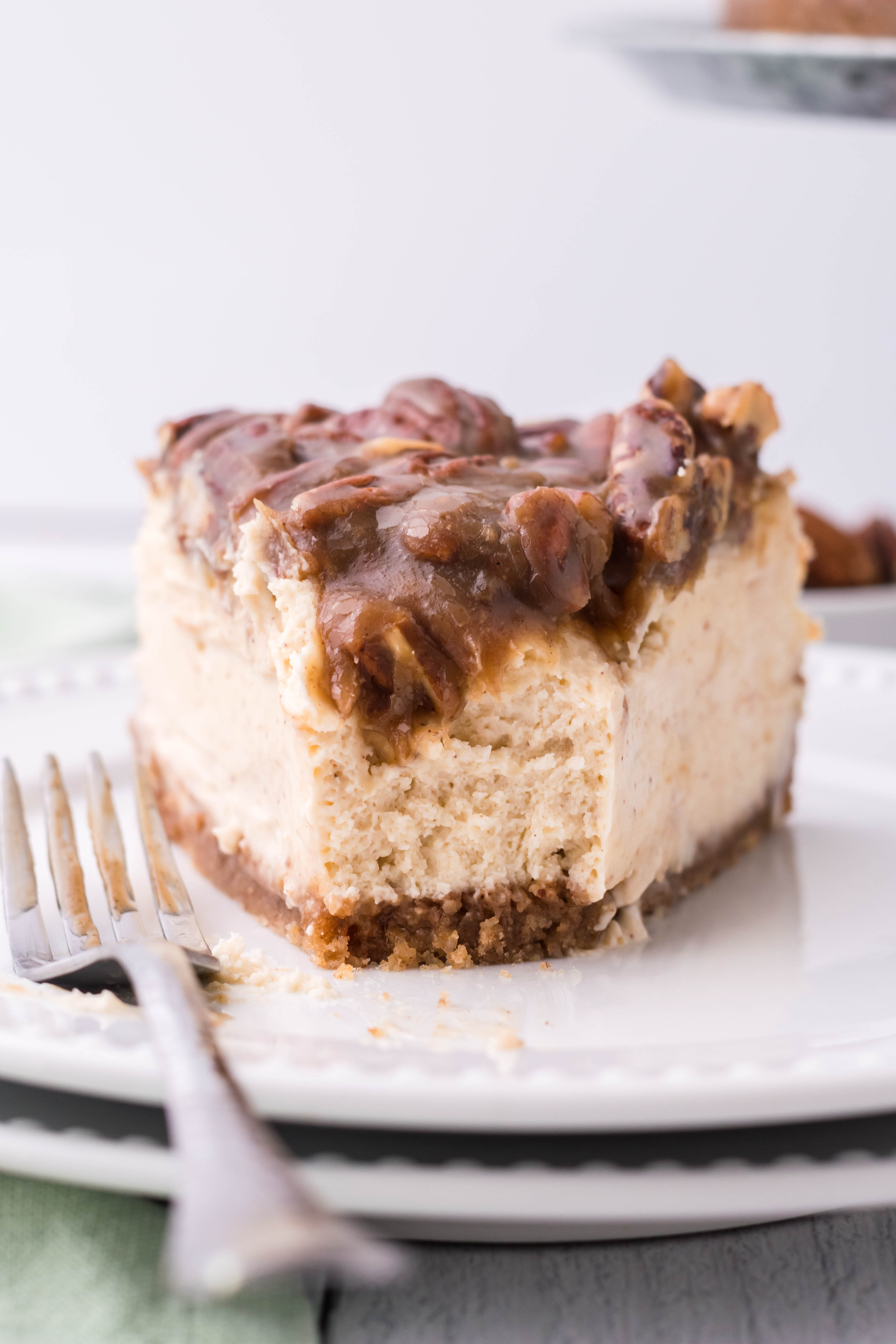 pecan pie Cheesecake slice on a white plate with a bite missing