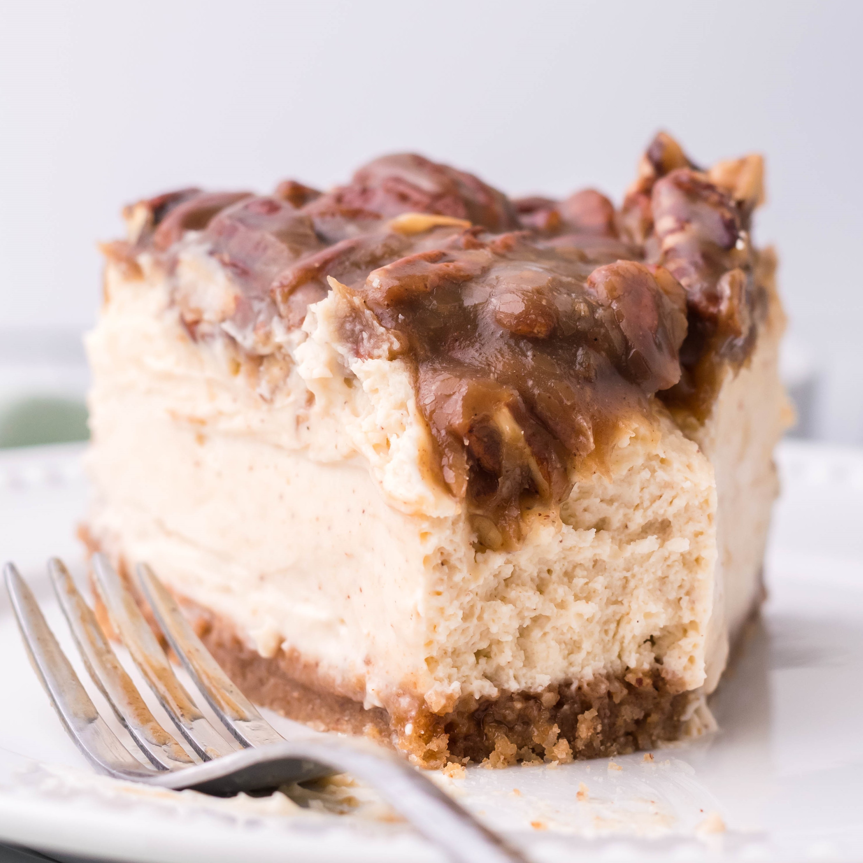 pecan pie Cheesecake slice on a white plate with a bite gone