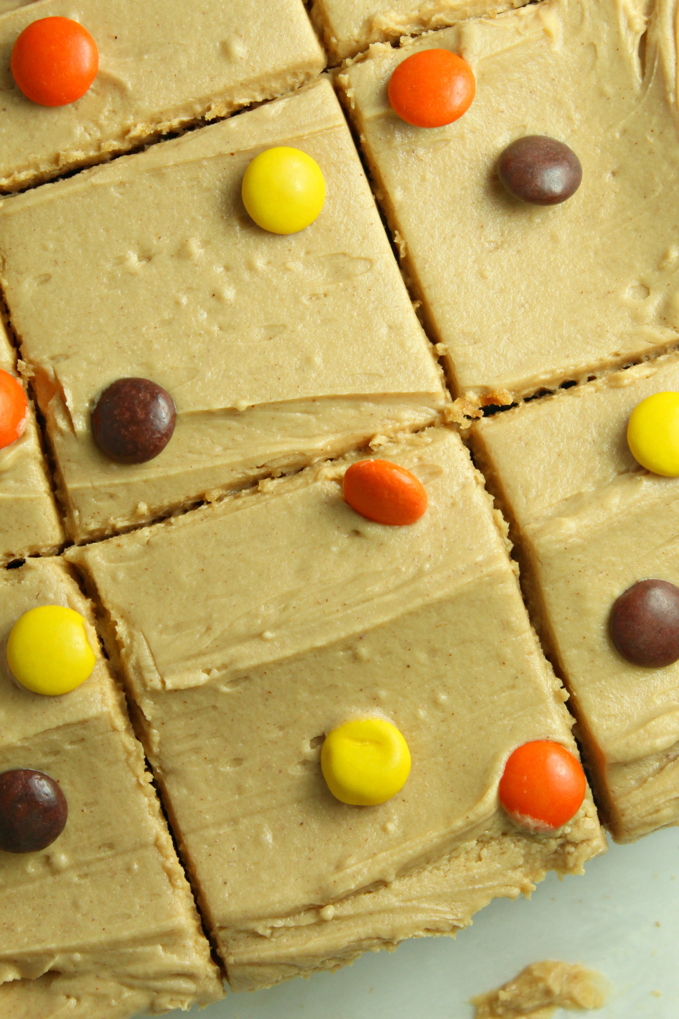 Peanut Butter Bars topped with peanut butter frosting & reeses pieces in a baking pan cut