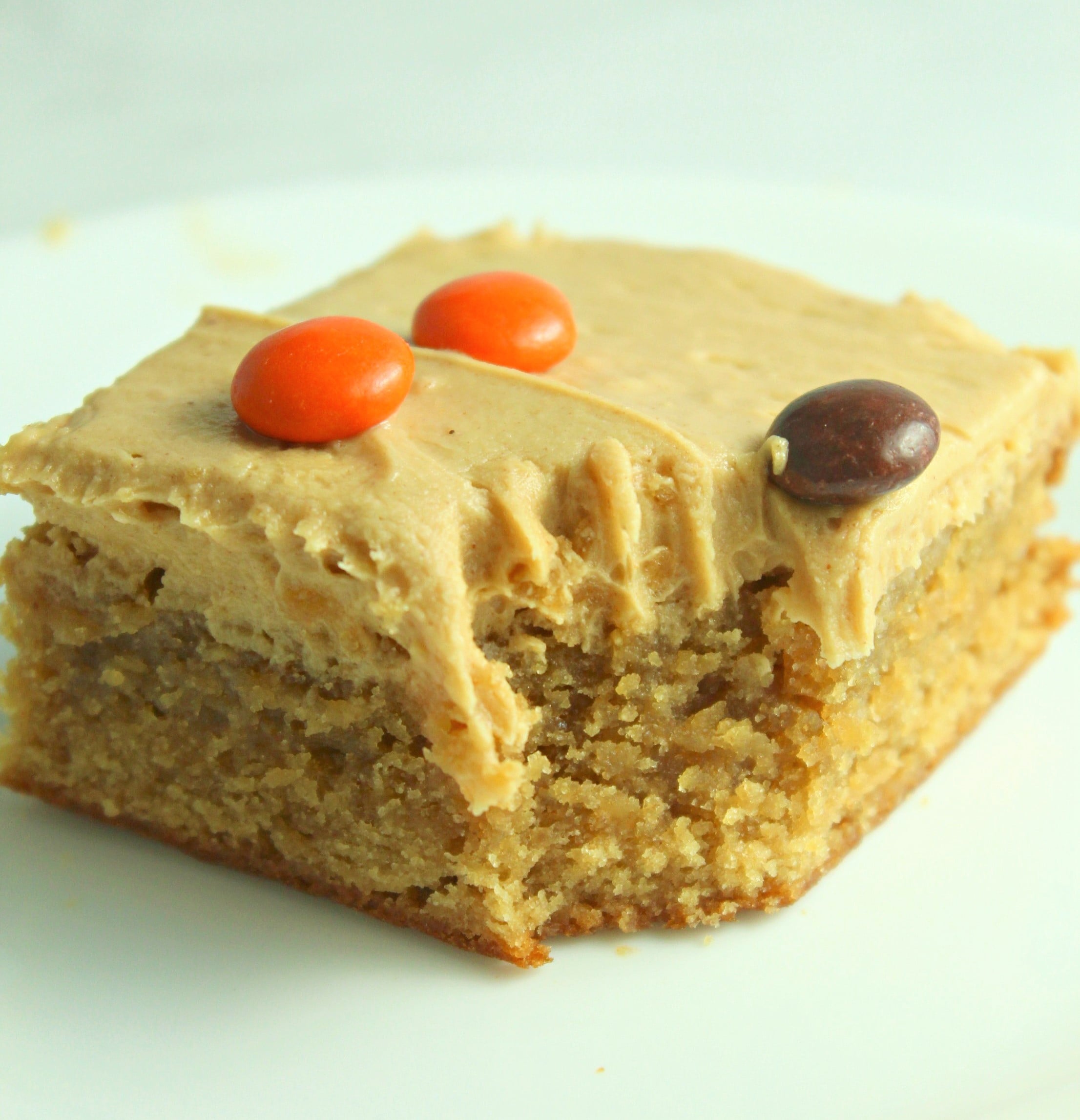 Peanut Butter Bars topped with peanut butter frosting & reeses pieces with a bite gone