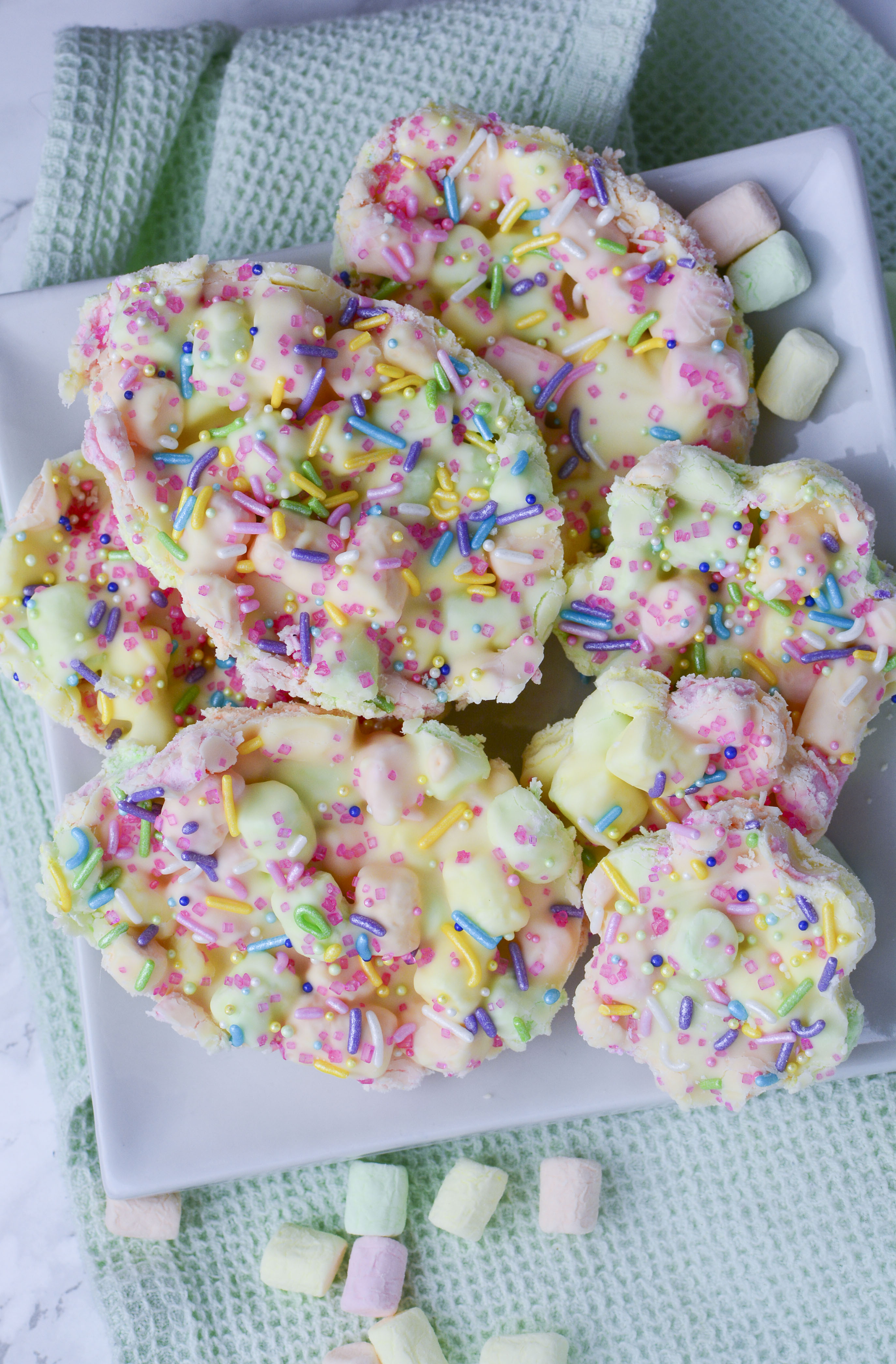 Easter Marshmallow treats with pink, green and yellow mini marshmallows cut into the shape of eggs on a white plate