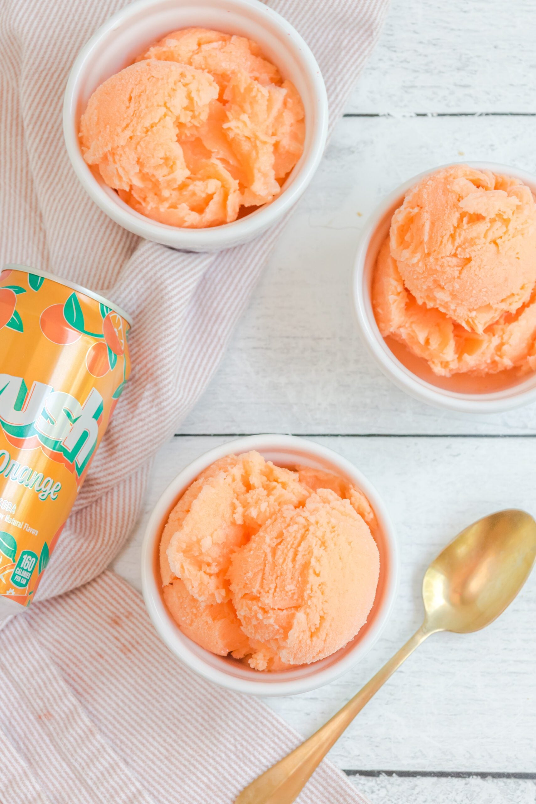 Orange Crush Sherbet in three white bowls with a can of orange crush next to them