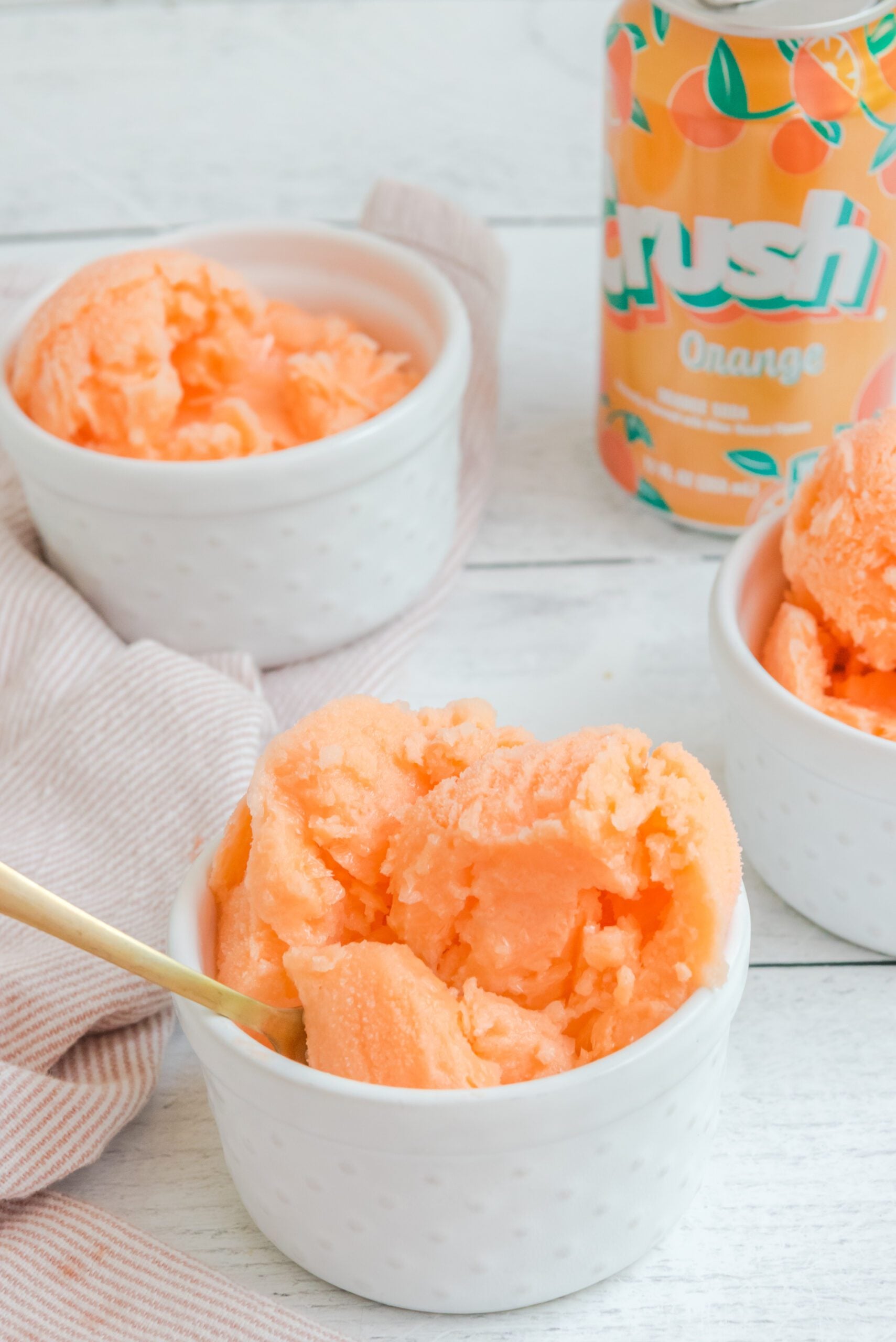 Orange Crush Sherbet in a white bowl with a gold spoon in it